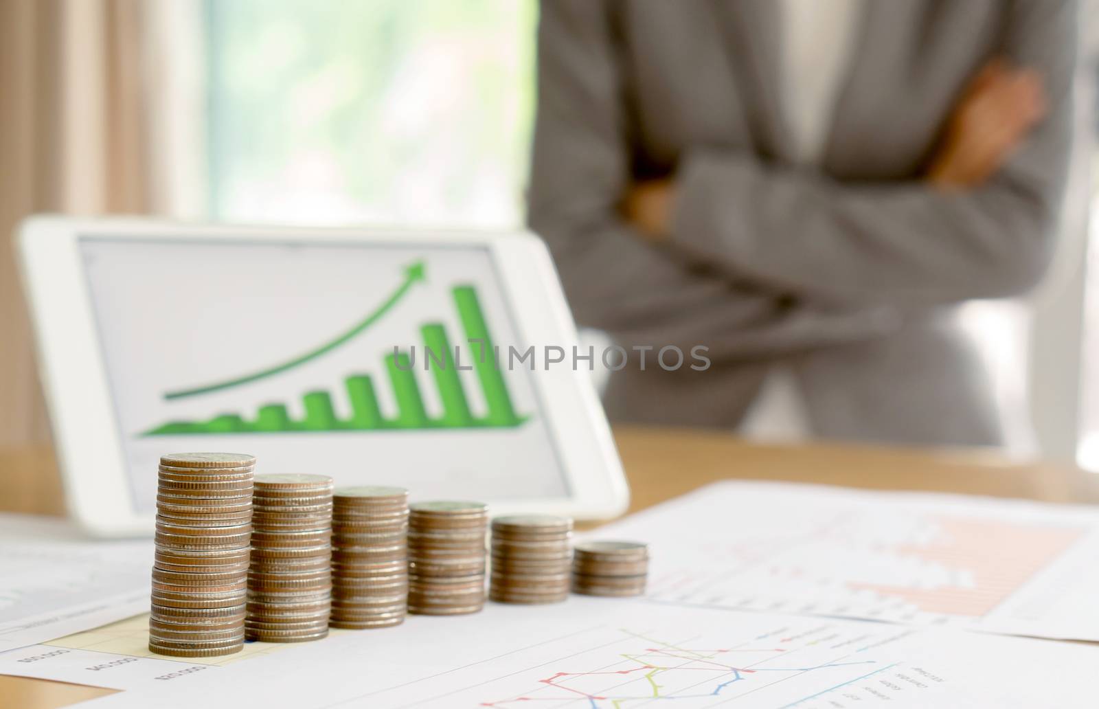 Grow up coins stack with business and finance graph screen on laptop computer on desk of investor adviser. Businesswomen background 