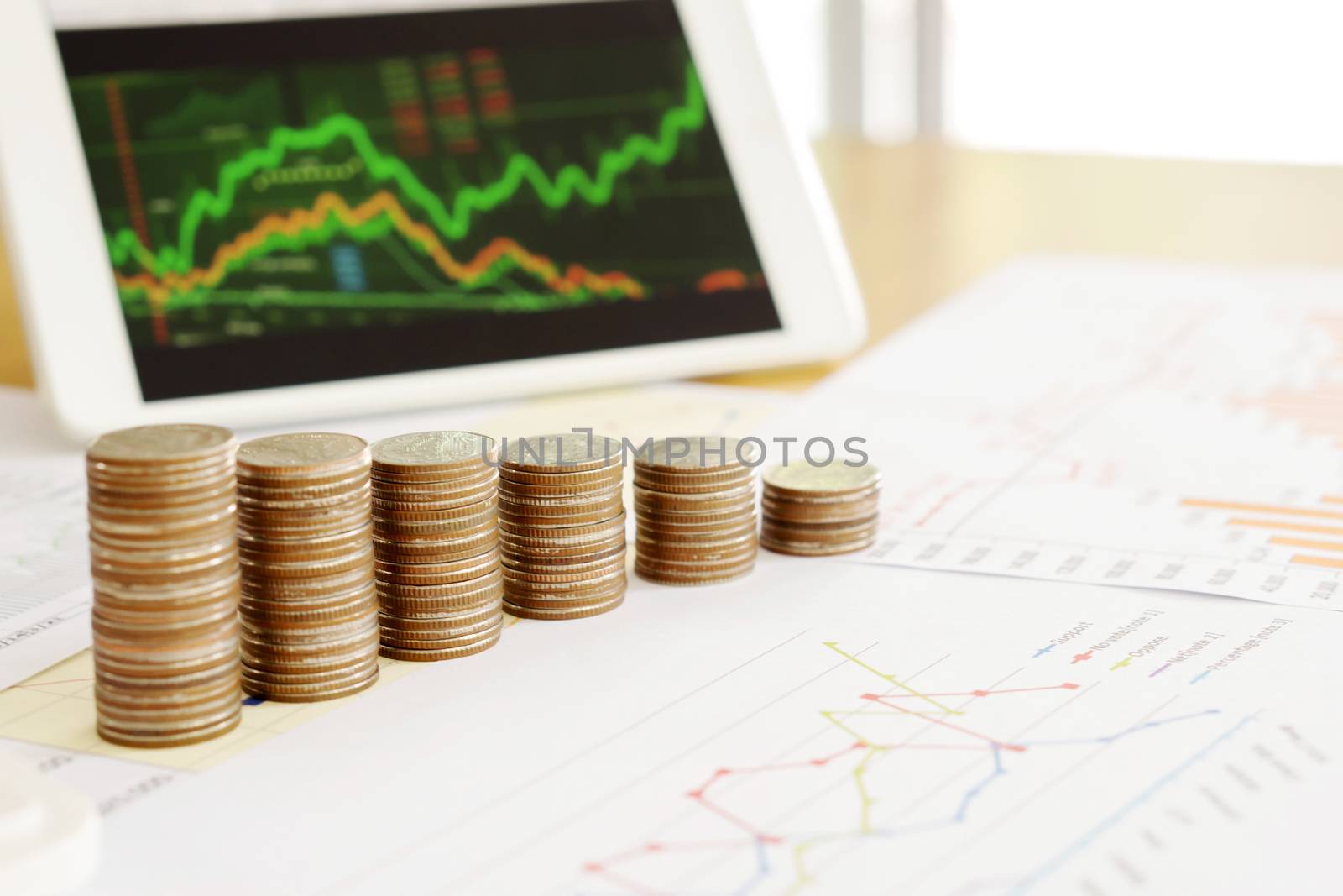 Grow up coins stack with business and finance graph screen on laptop computer on desk of investor adviser. Concept of financial and investment growth.