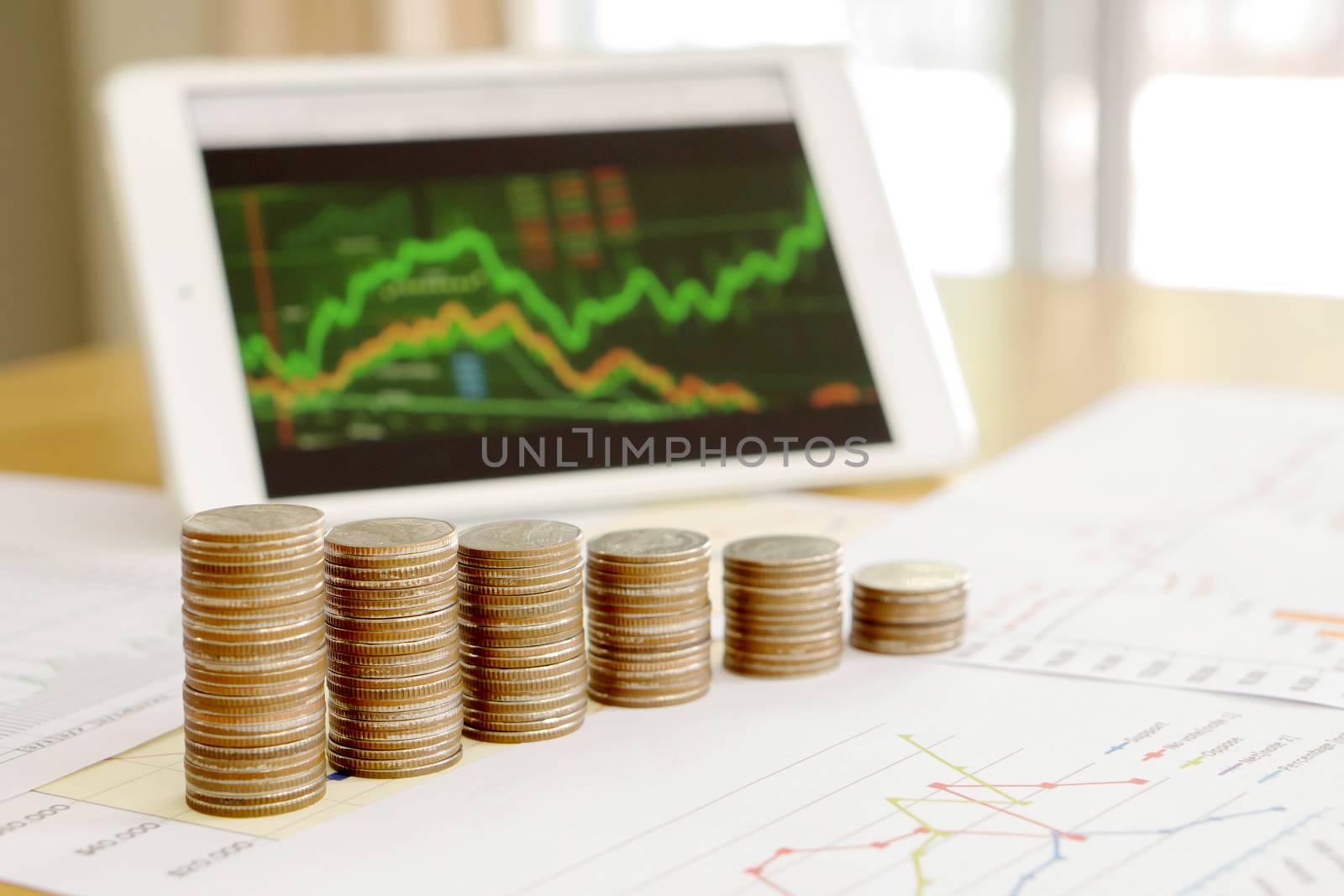 Grow up coins stack with business and finance graph screen on laptop computer on desk of investor adviser. Concept of financial and investment growth.