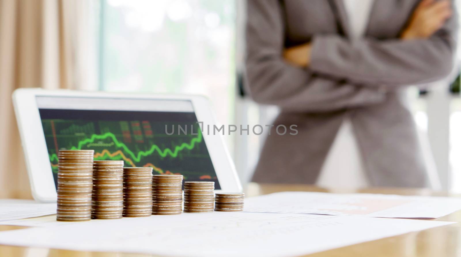Grow up coins stack with business and finance graph screen on laptop computer on desk of investor adviser. Businesswomen background 