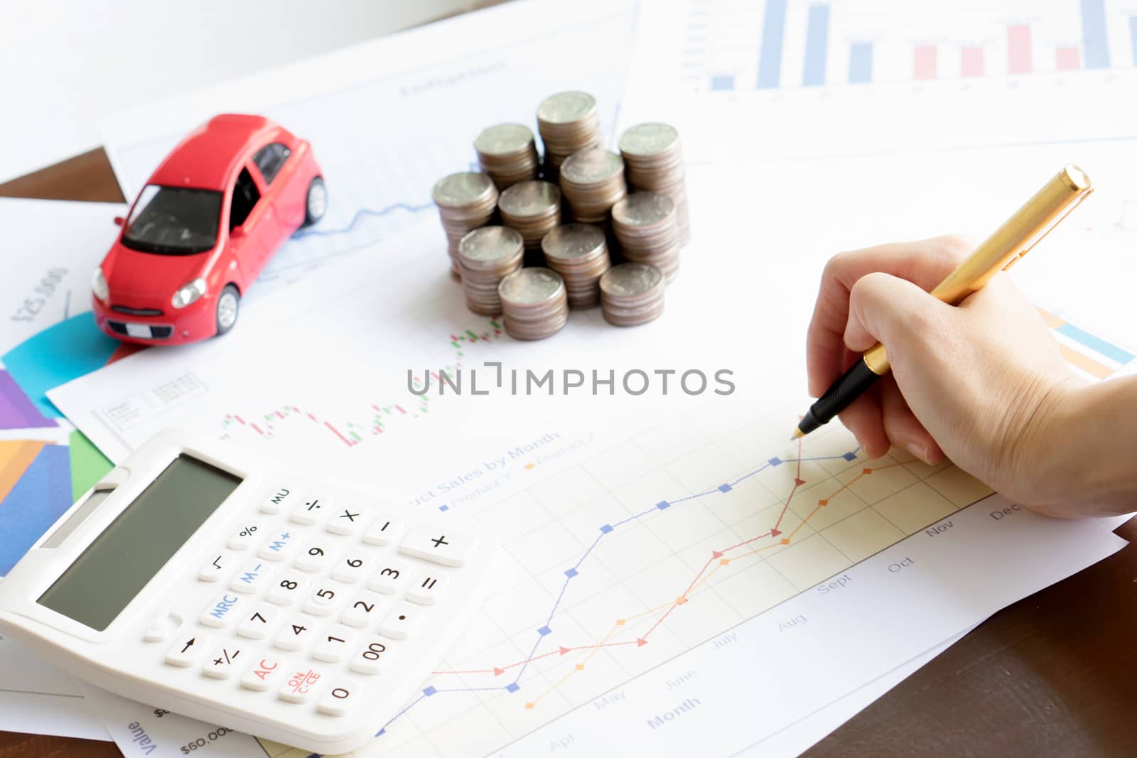 Hand hold a pen and press calculator and toy car and coins and business chart with sun lights color tone backgrounds