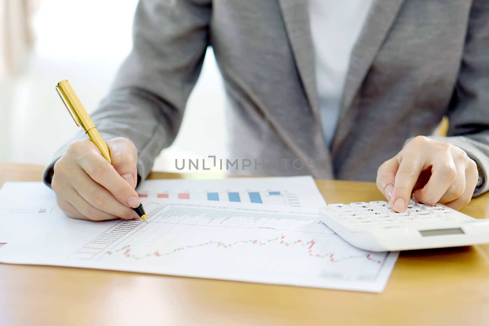 Close-up Of Businesswoman Analyzing Financial Report With Calculator At Wooden 