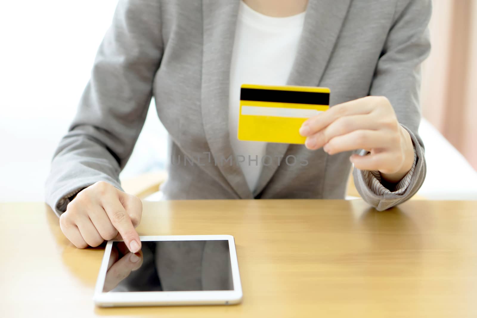 Close-up woman's hands holding a credit card and using tablet pc 