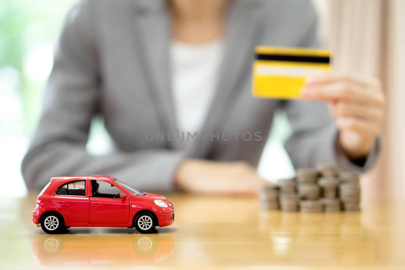 Businesswoman hand hold credit card, a toy car and a stack of coins