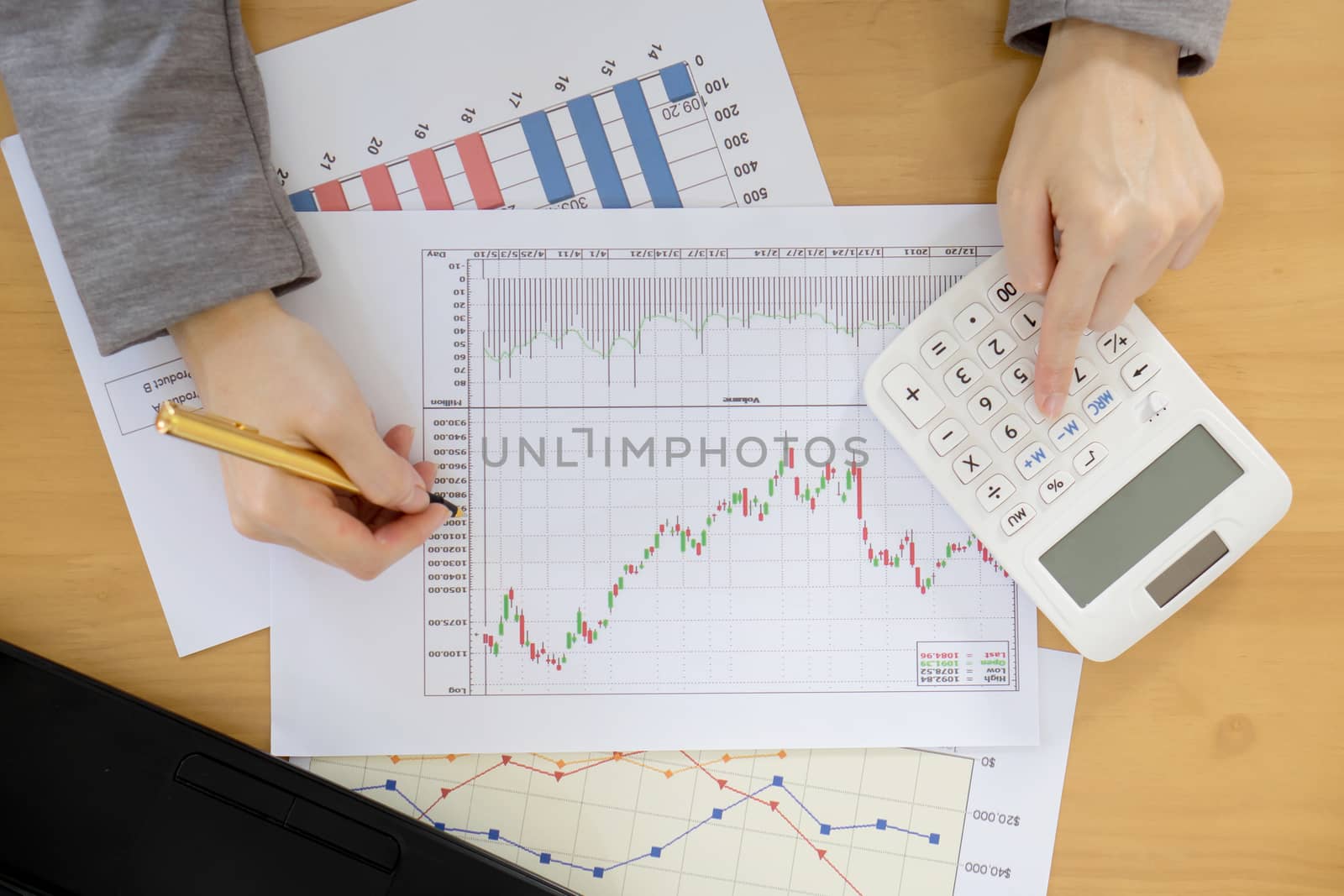 Businesswoman using calculator while analyzing graphs