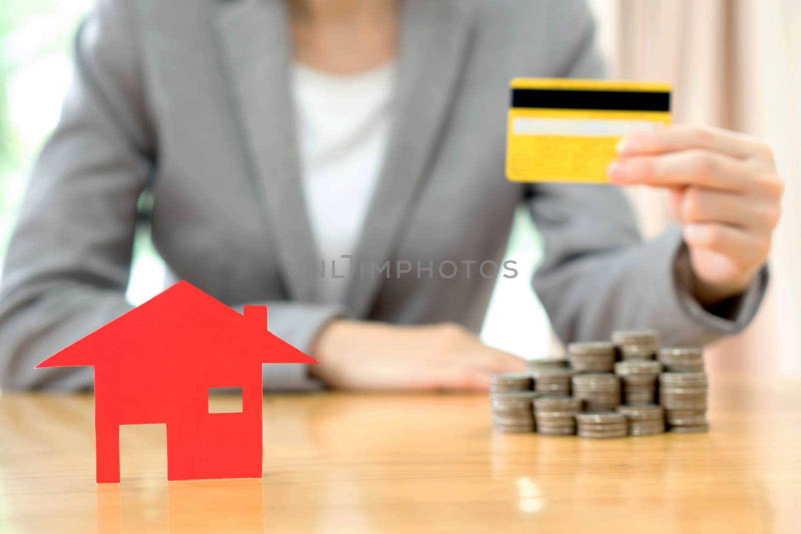 Real estate investment by credit card. House and coins on table.