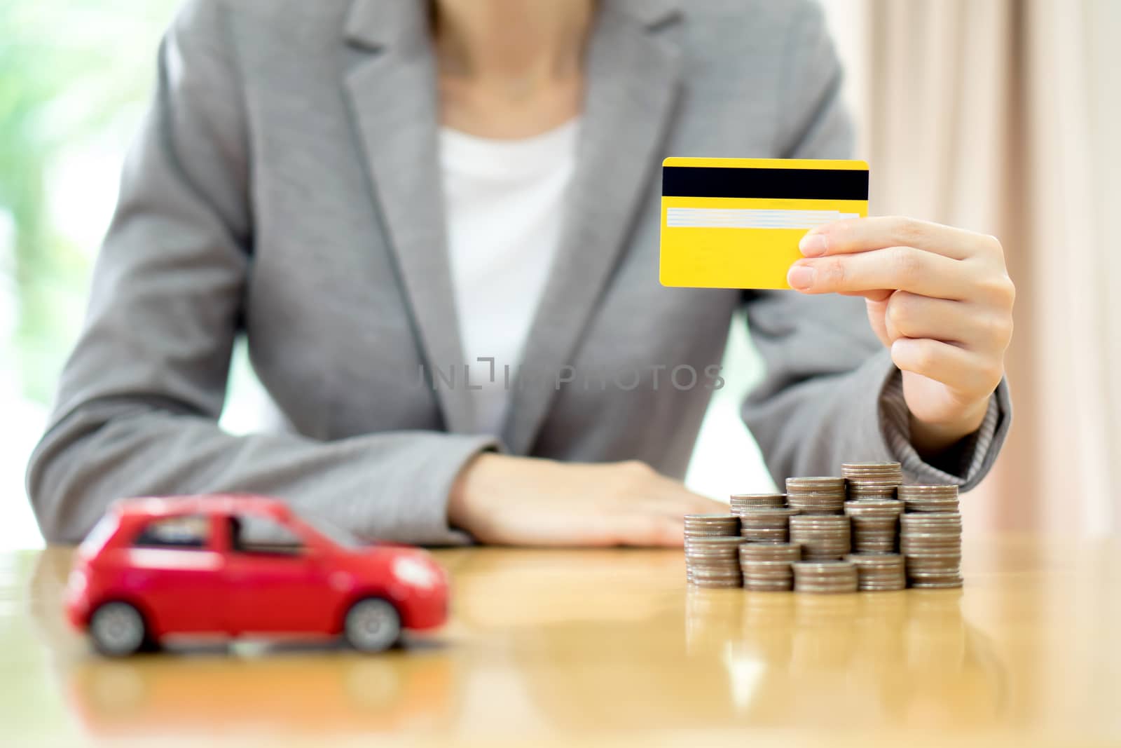 Businesswoman hand hold credit card, a toy car and a stack of coins