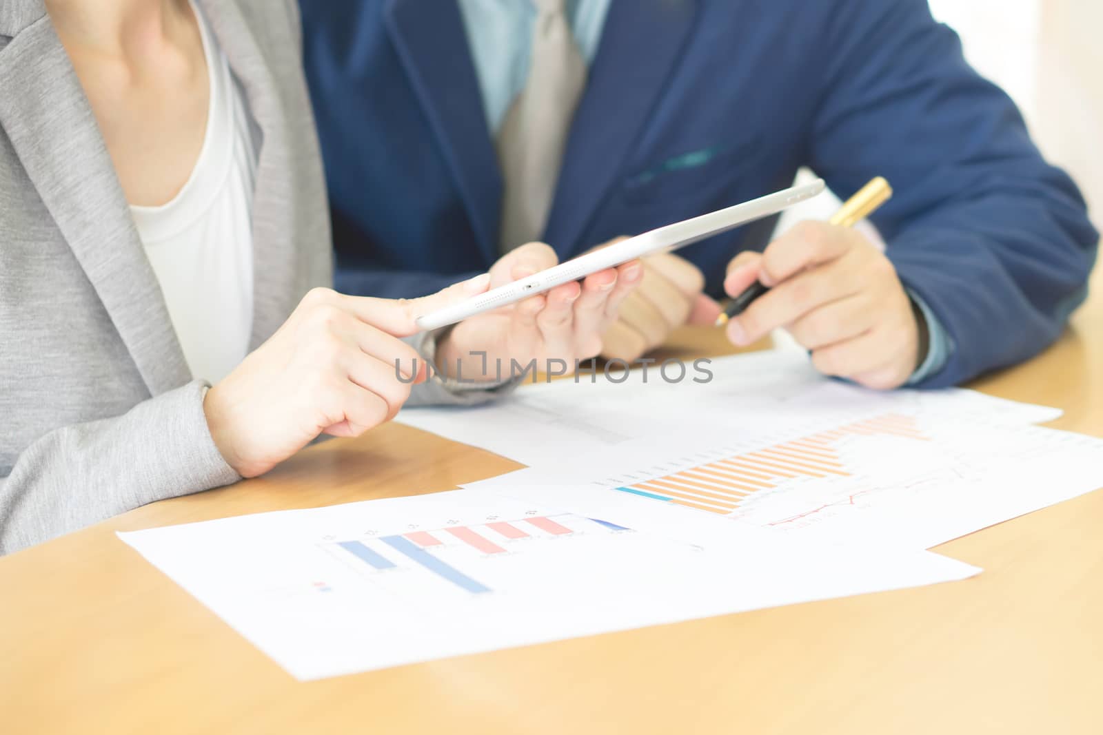 Image of two young business partners using touchpad at meeting