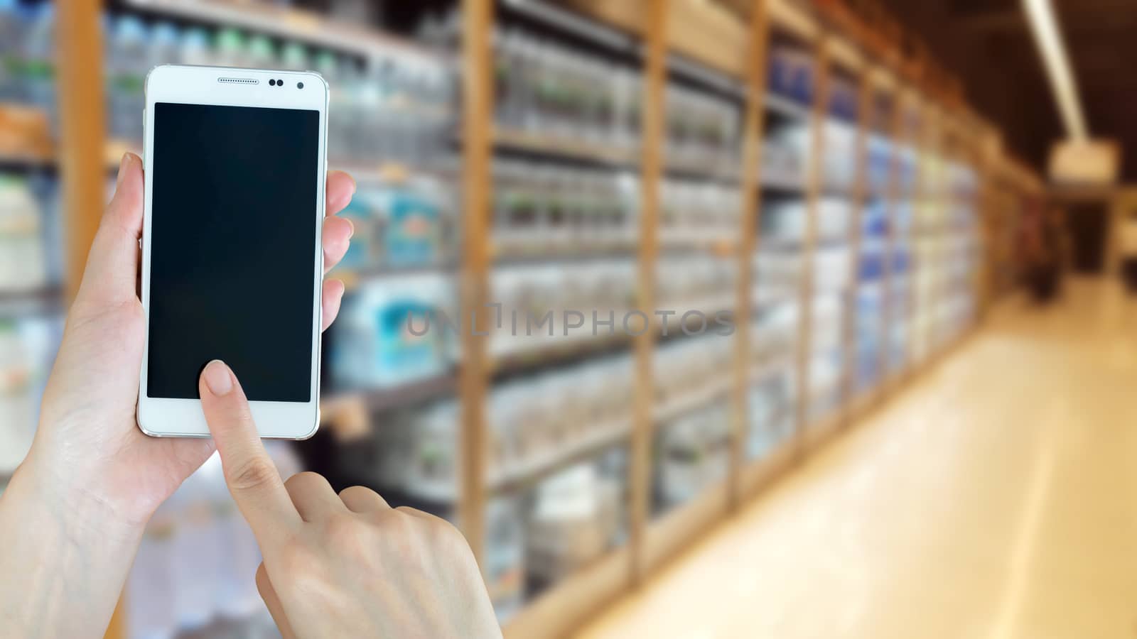 Woman using smart phon while shopping in supermarket
