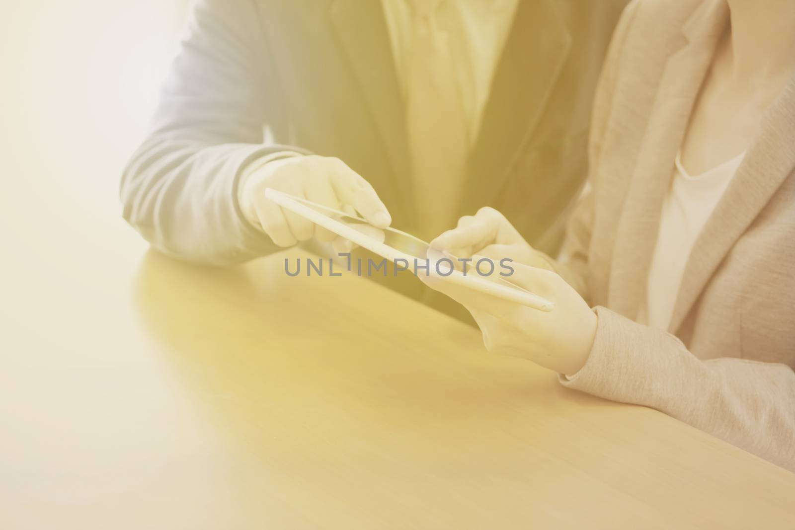 Two confident businesspeople using a digital tablet together while working at a table