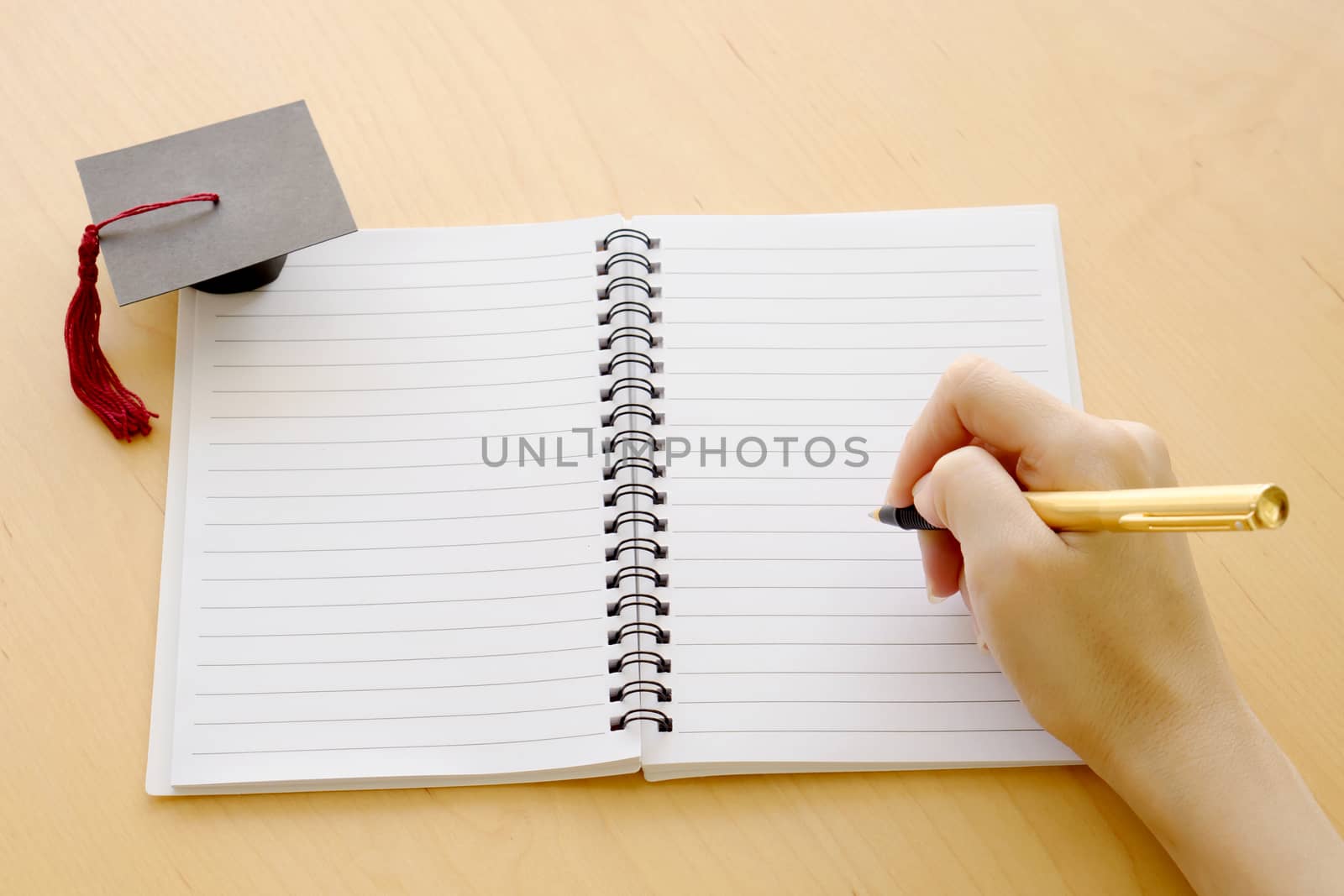 Blank notebook on the table and graduation cap