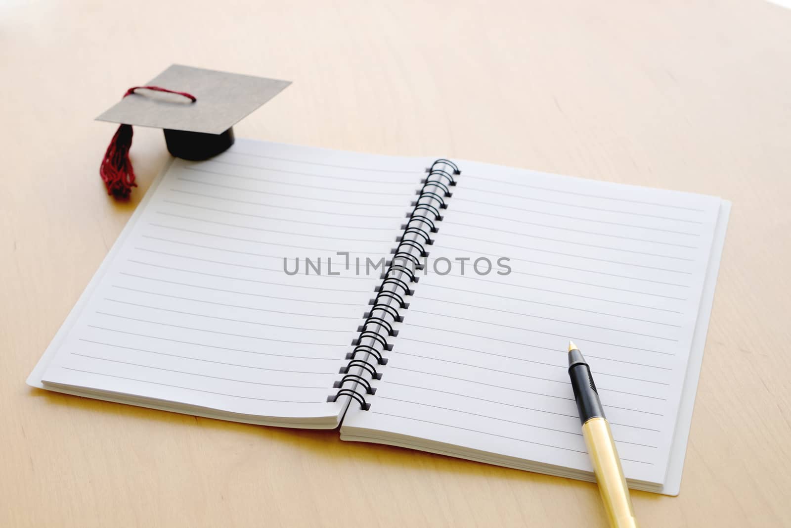 Blank notebook on the table and graduation cap