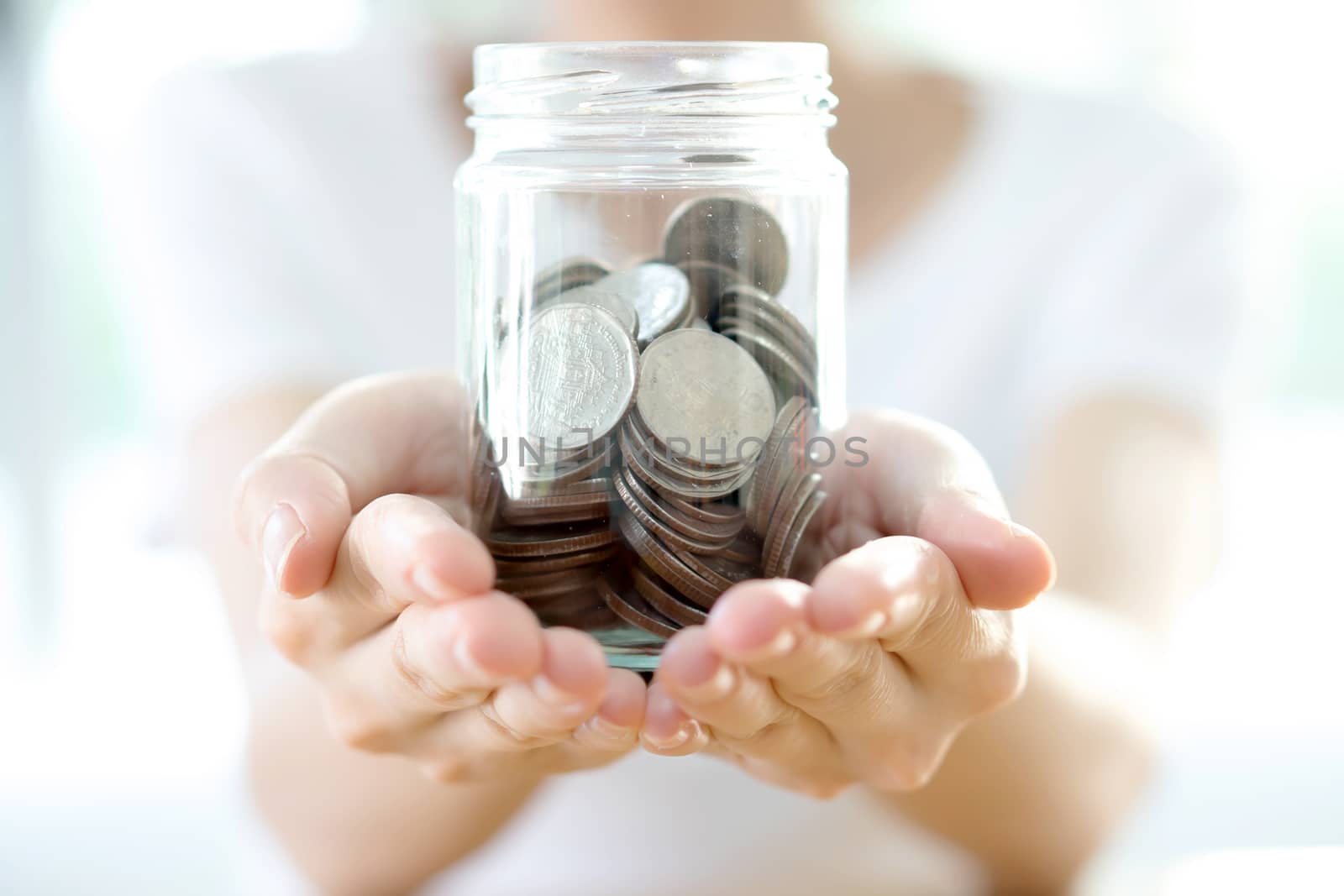 Woman holding money jar with coins close up 
