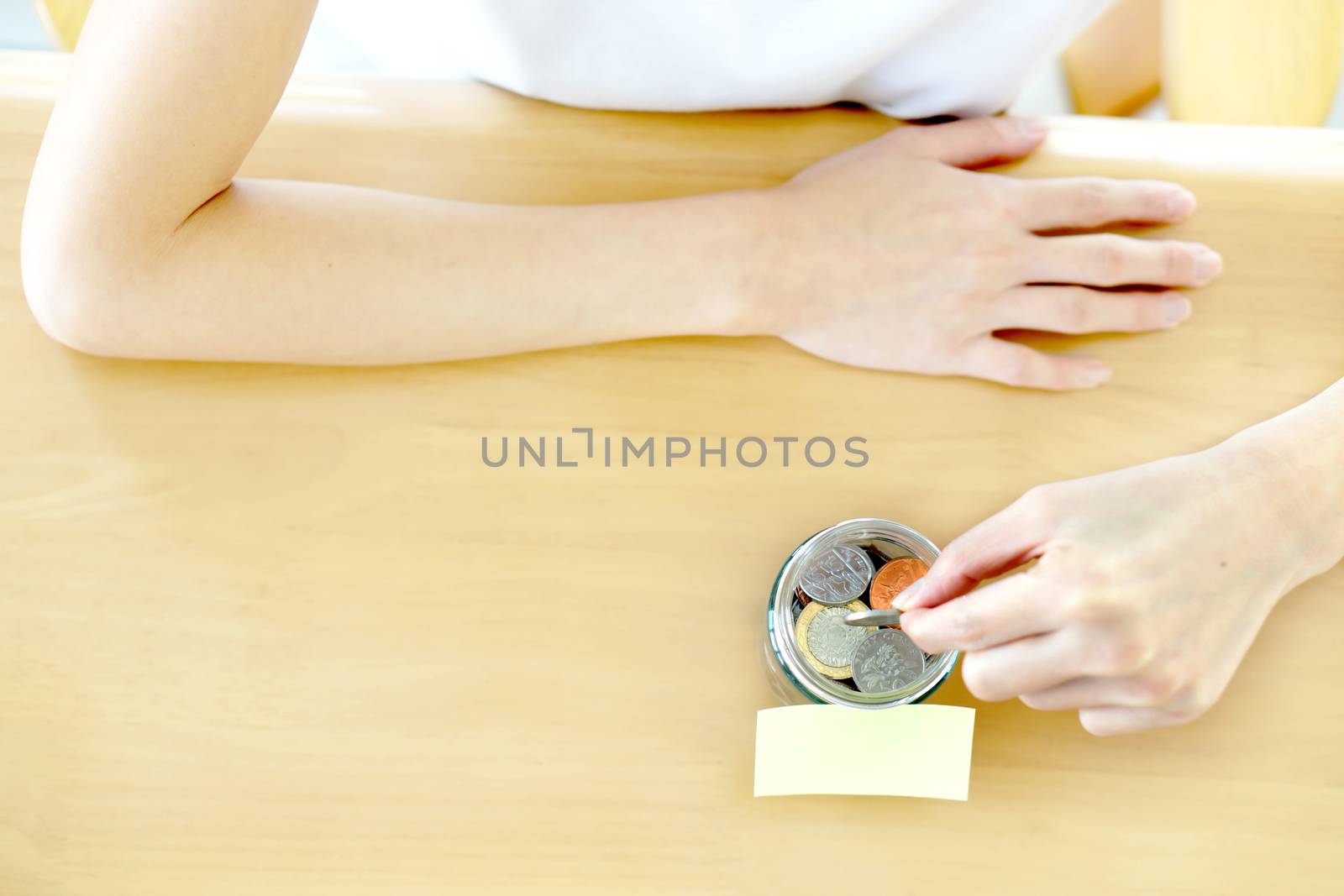 Woman hands with coins in glass jar, top view