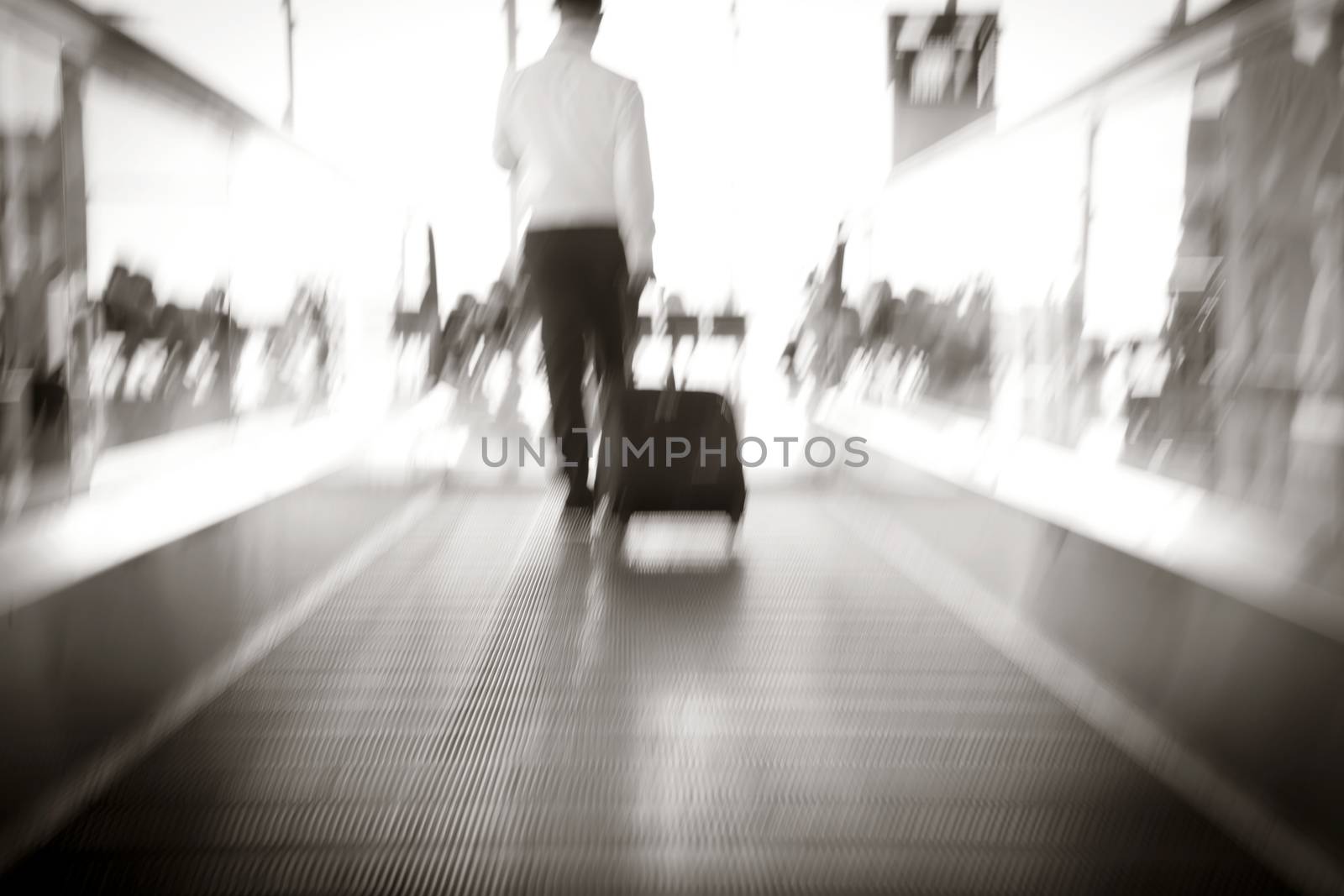 Blur, Businessman dragging a small carry on luggage suitcase at airport corridor walking to departure gates