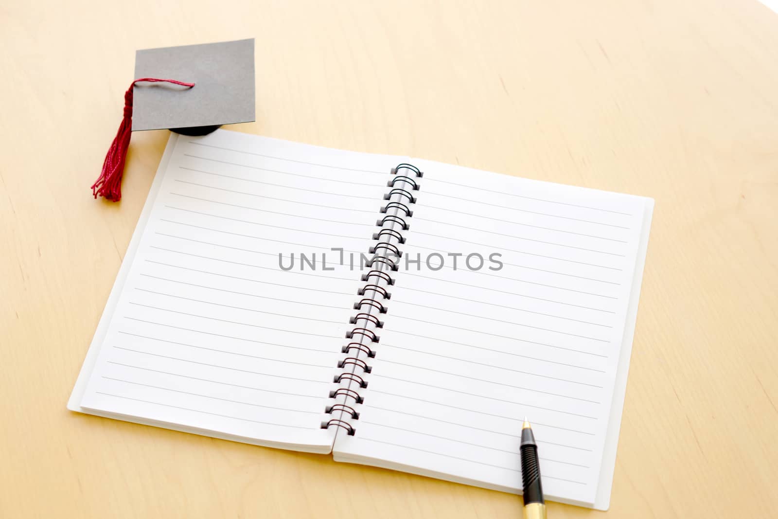 Blank notebook on the table and graduation cap