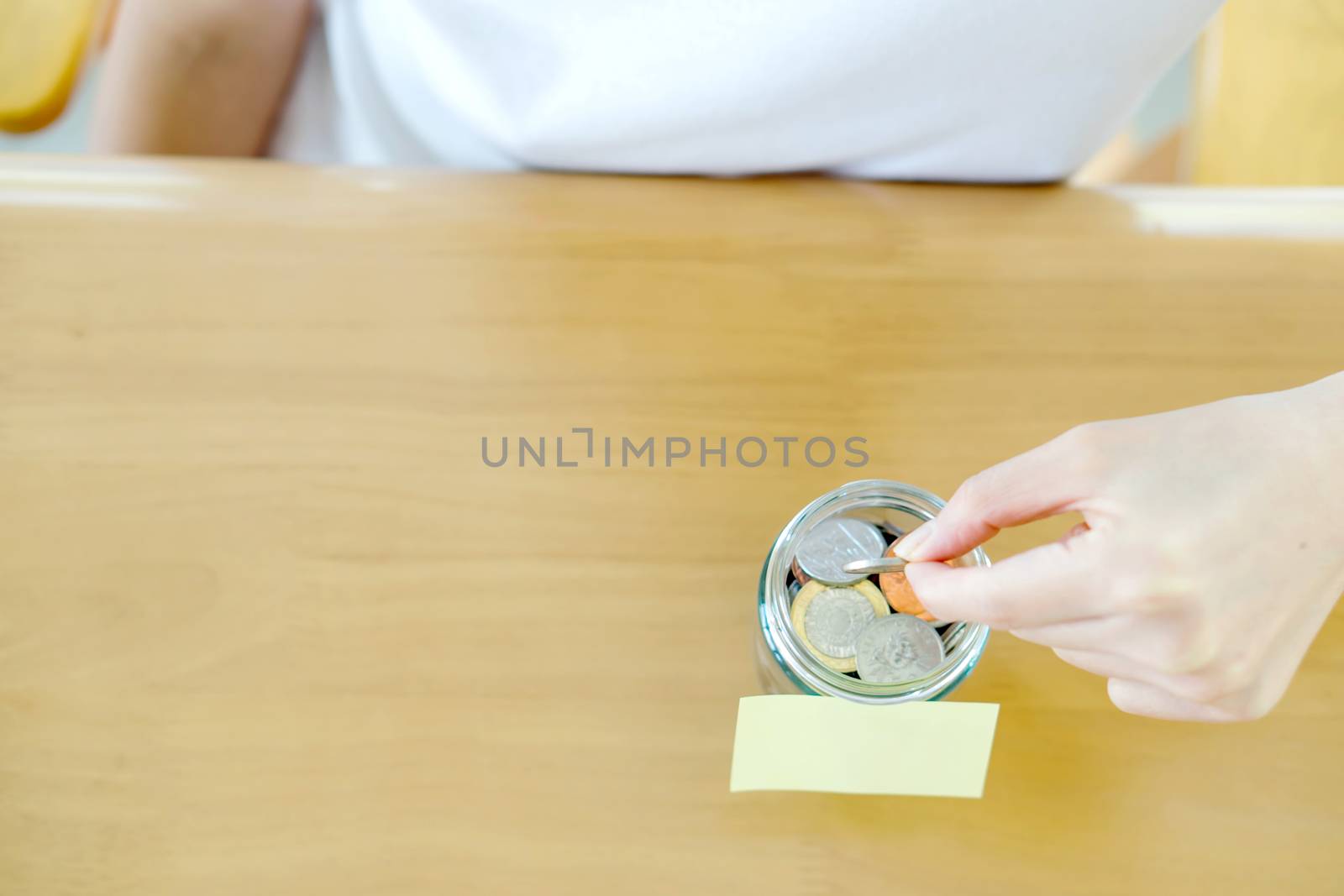 Woman hands with coins in glass jar, top view