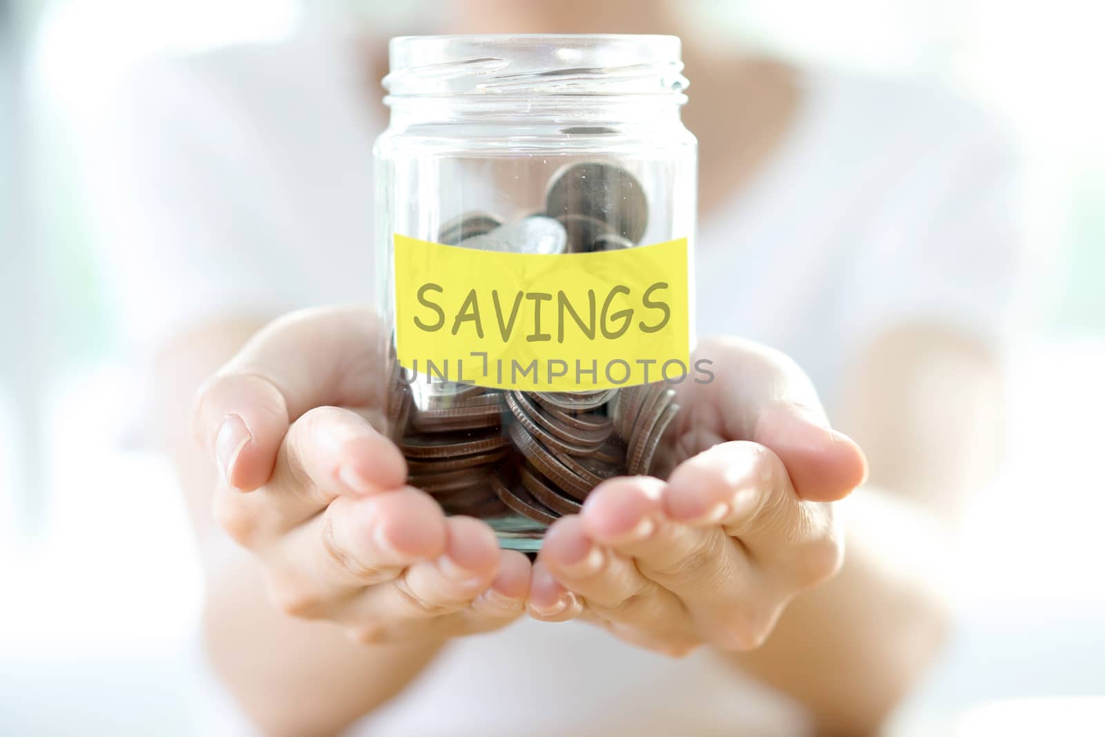 Woman holding money jar with coins close up 