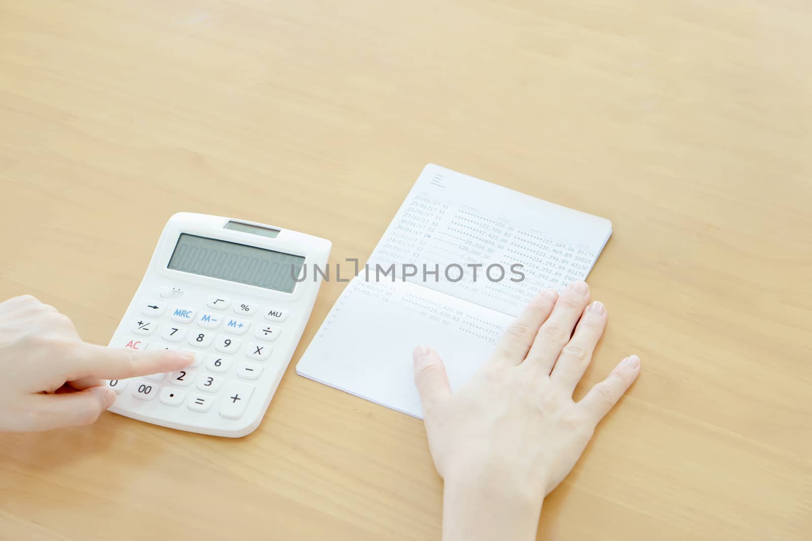 Businesswoman use calculator beside passbook  by ekachailo