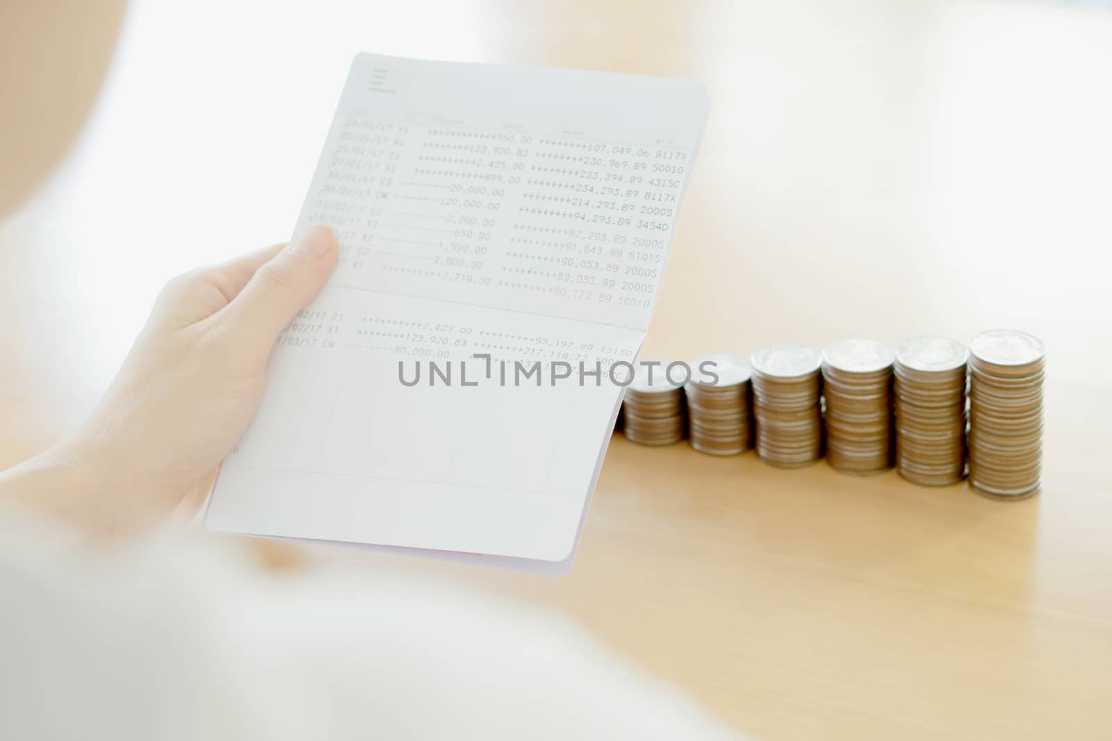 Woman hold passbook on hand, coins background