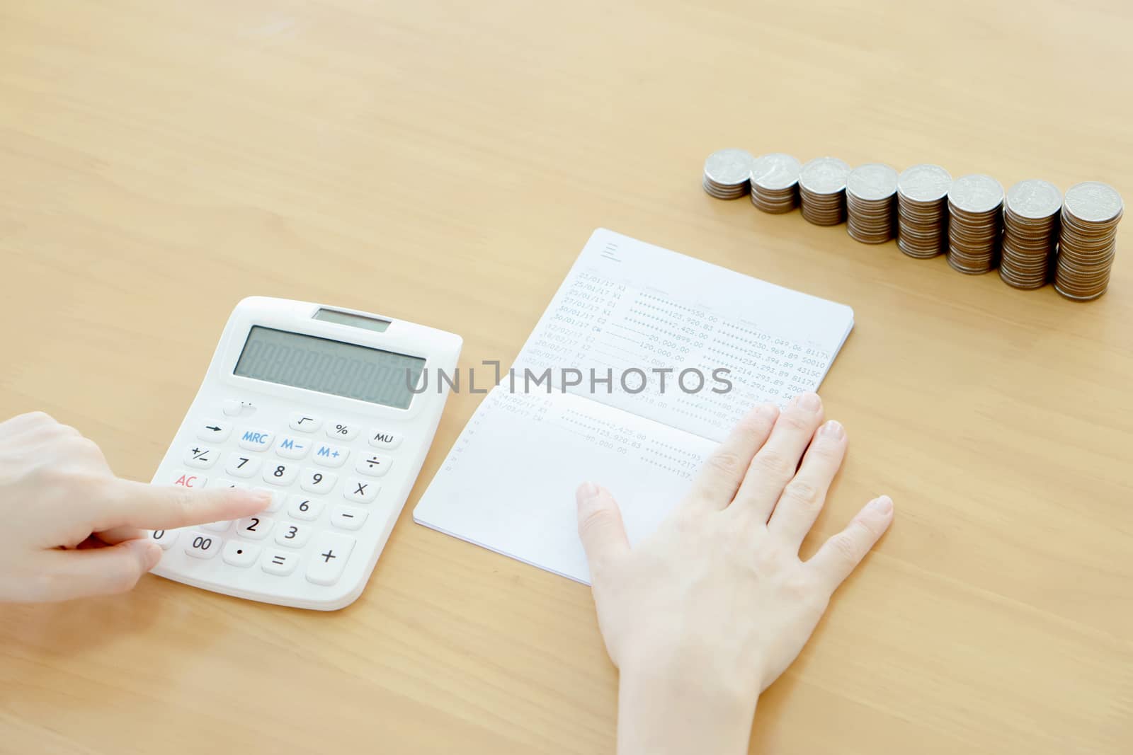 Businesswoman use calculator beside passbook and Coins