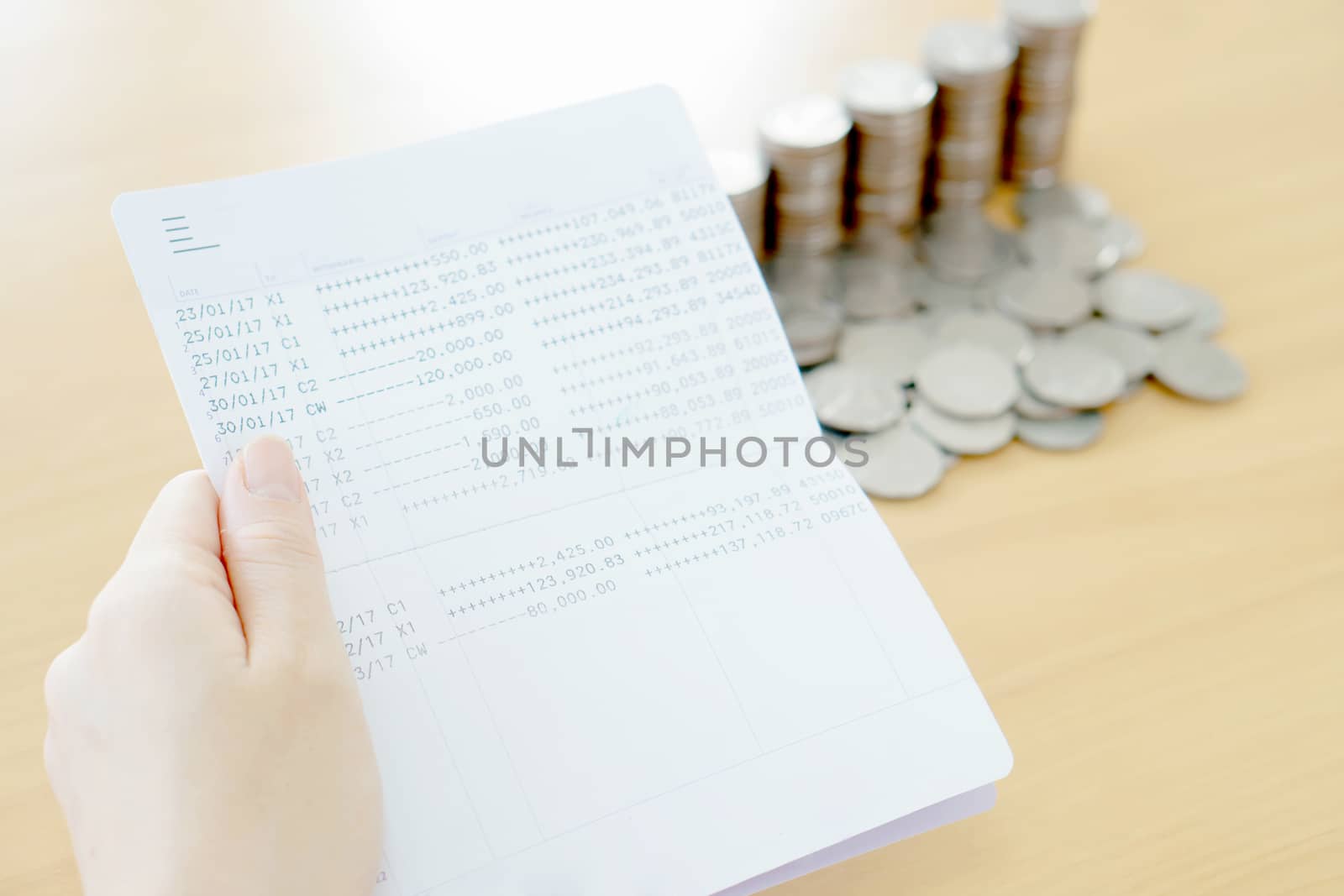 Woman hold passbook on hand, coins background