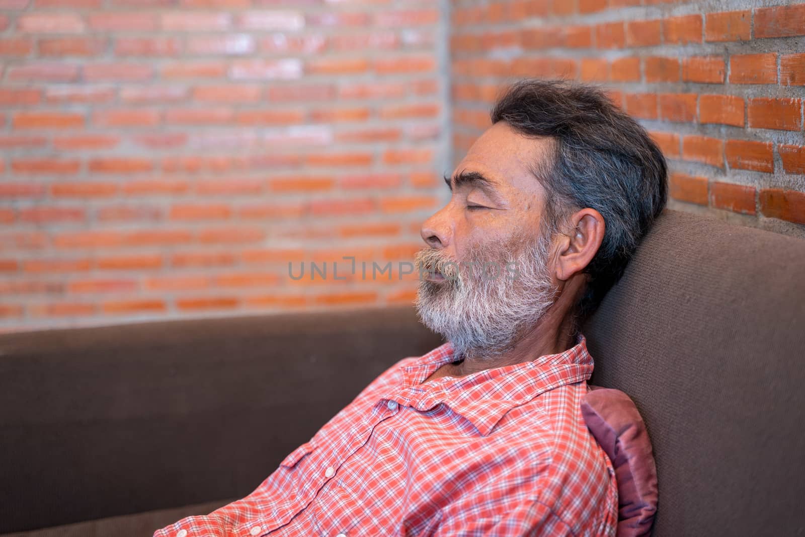 Elderly man taking a nap in sofa at home.