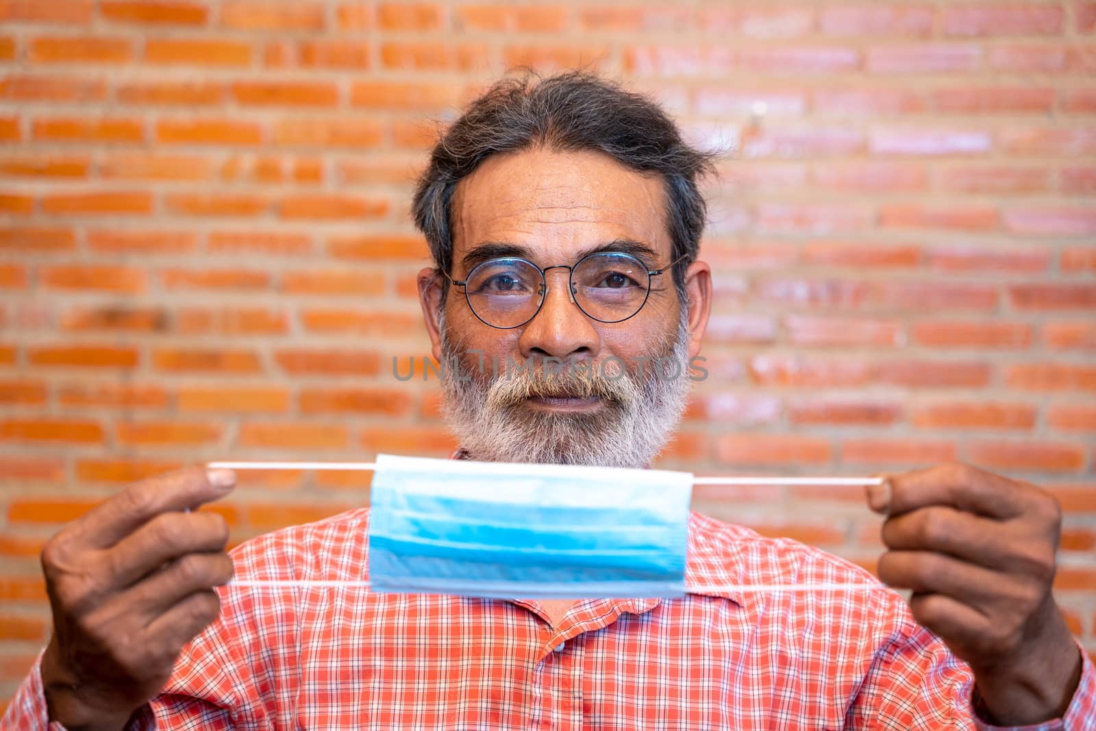 Portrait of smiling senior man ready to wearing protective mask by Visoot