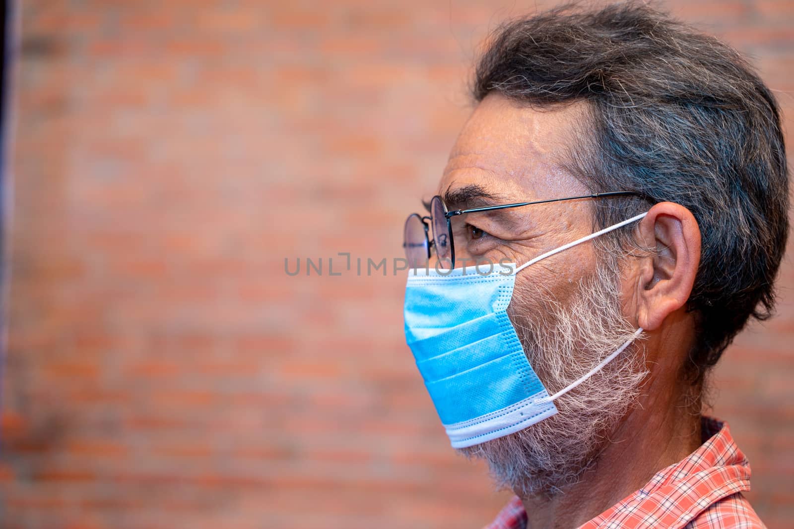 Elderly man wears protective mask against infectious diseases. by Visoot