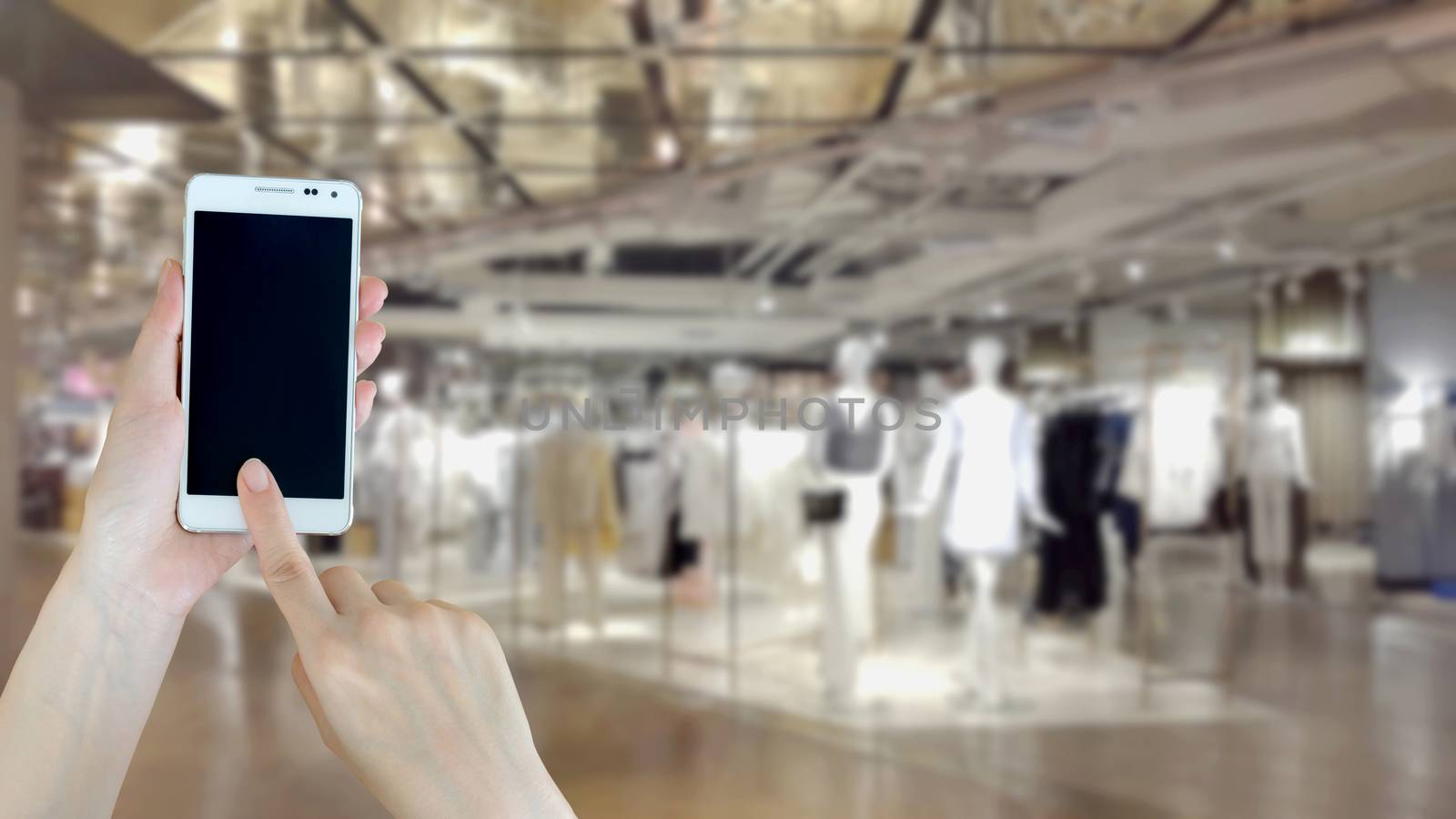 Woman using cellphone while shopping by ekachailo