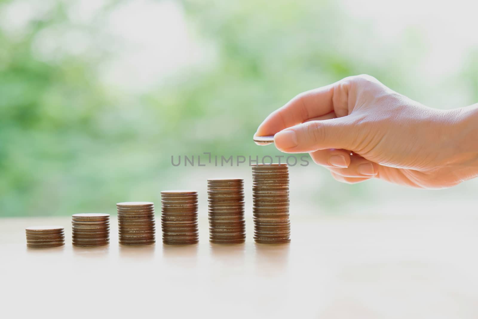 Hand giving coins into stack, business and finance concept