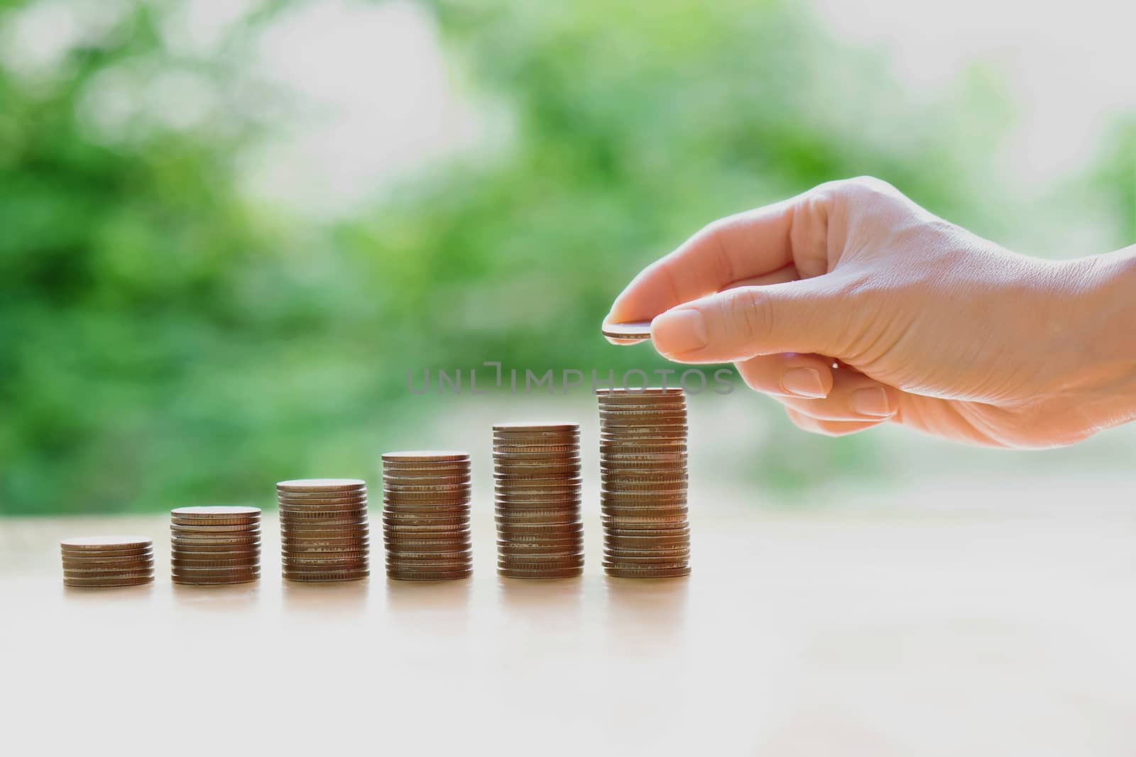 Hand giving coins into stack, business and finance concept