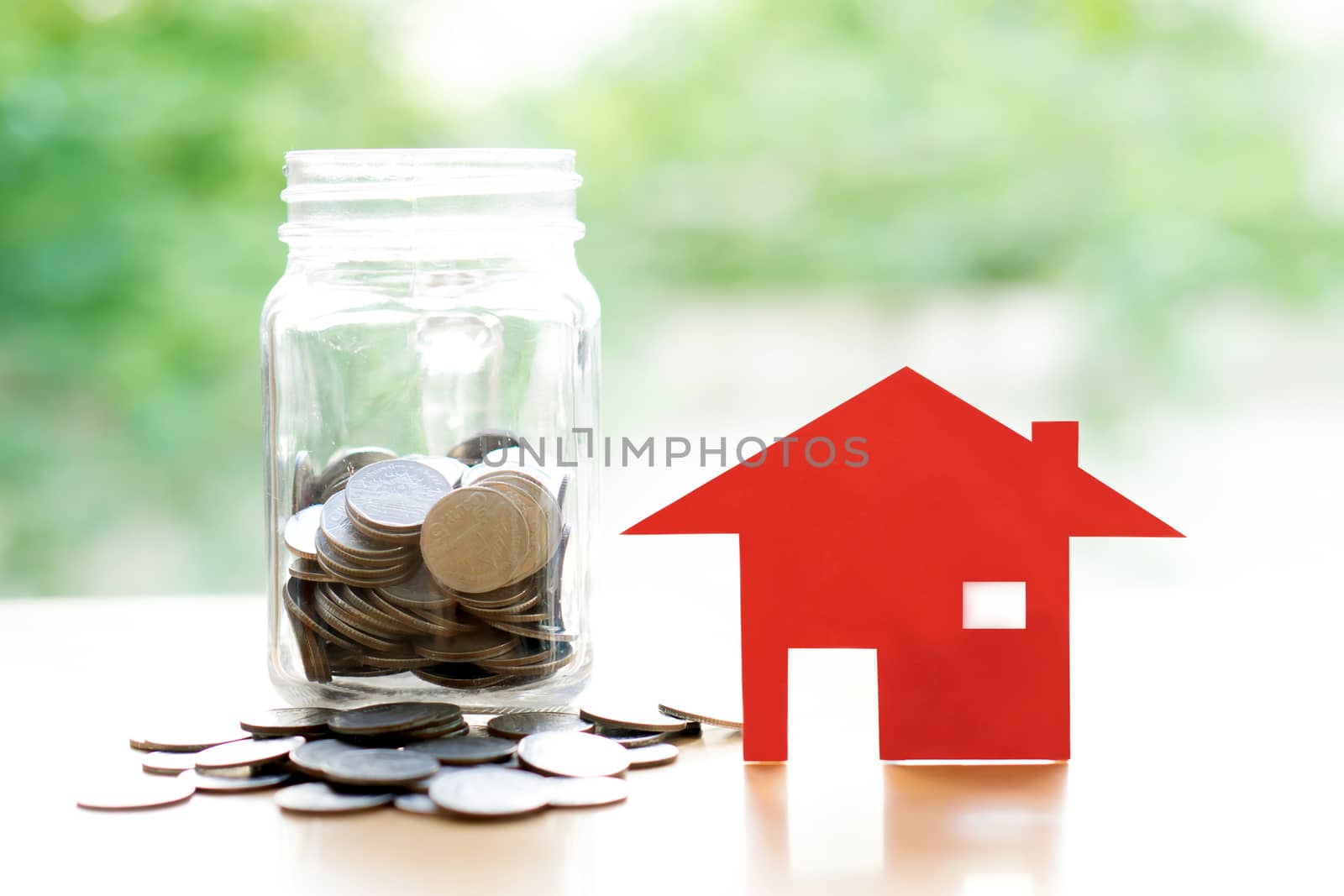 Coins in jar with red house. Saving for home concept