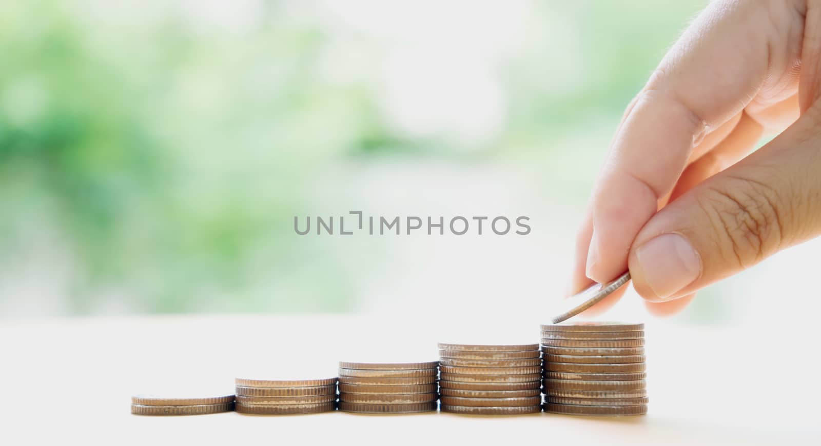 Close up of female hand stacking coins  by ekachailo