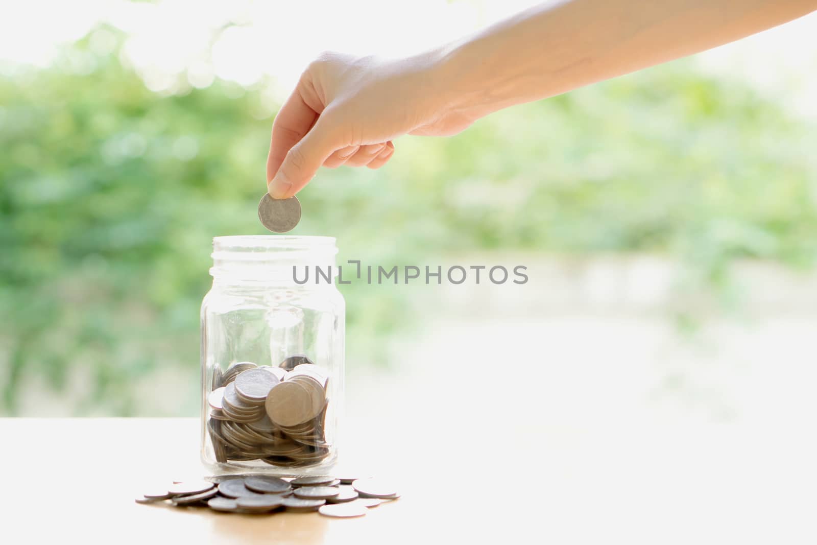 Woman Dropping Coins Into Glass Jar