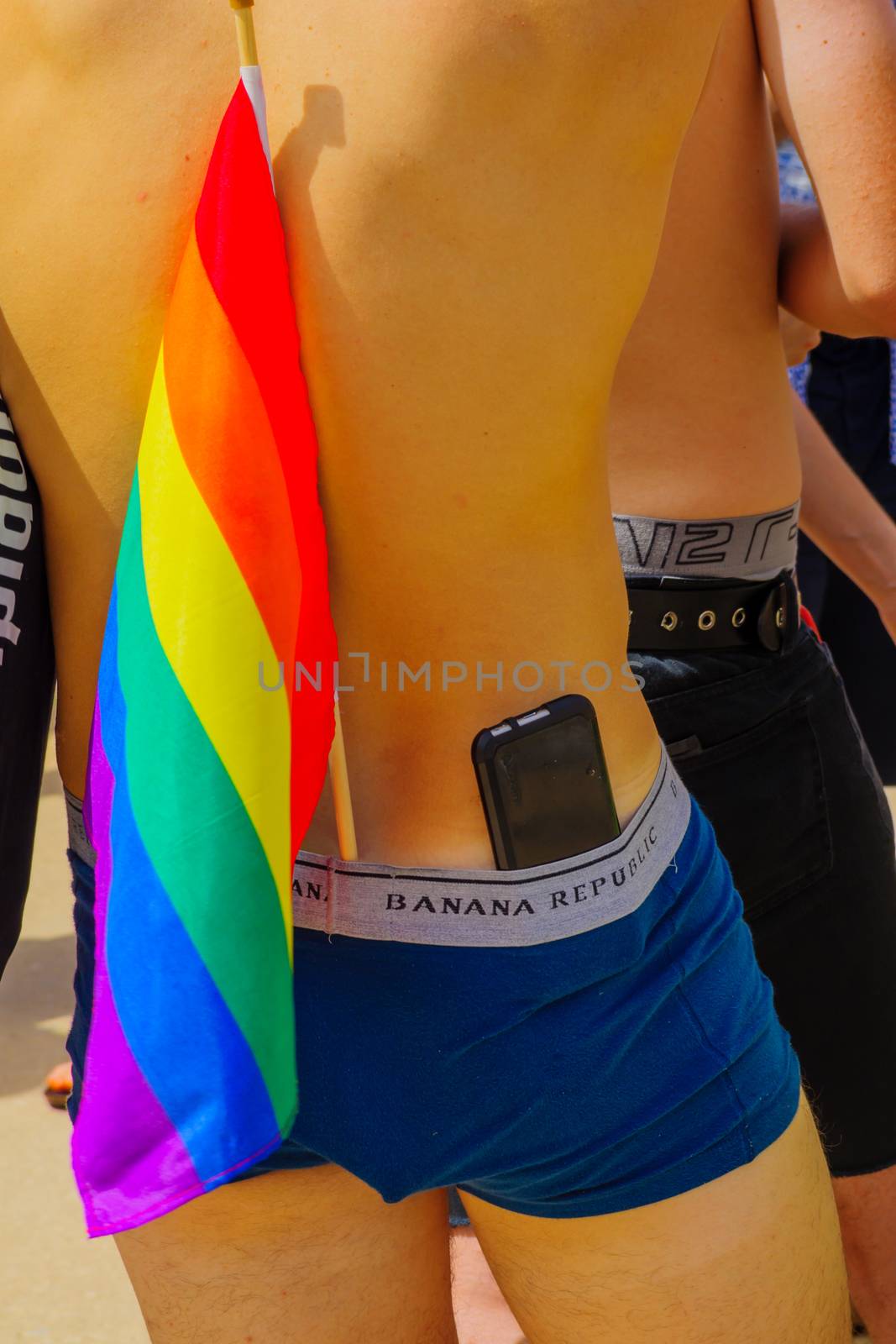 TEL-AVIV, ISRAEL - JUNE 03, 2016: Participant in the Pride Parade holds pride flag and phone, in Tel-Aviv, Israel. Its part of an annual event of the LGBT community