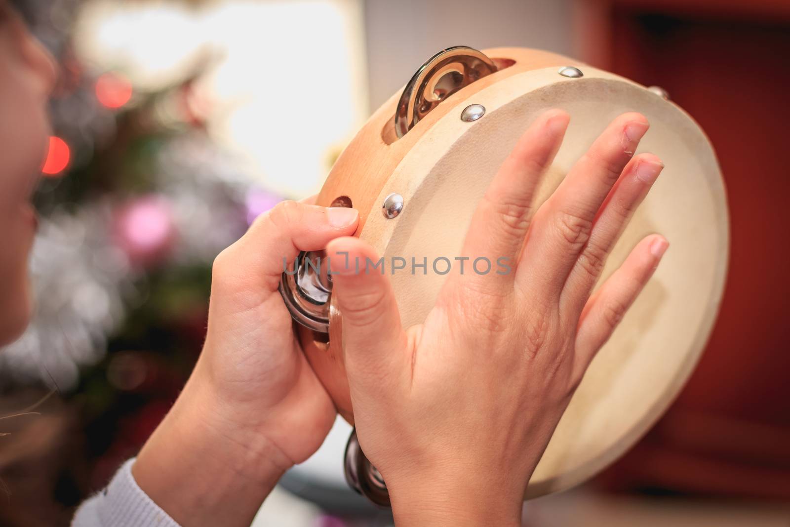 girl plays the tambourine in front of a Christmas tree by AtlanticEUROSTOXX
