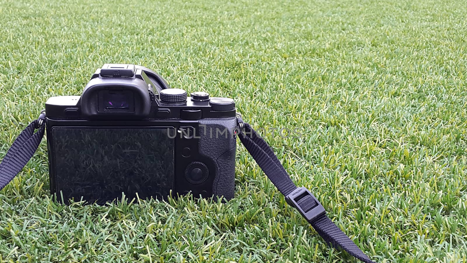 Digital photo camera on grass in summer.  by ekachailo