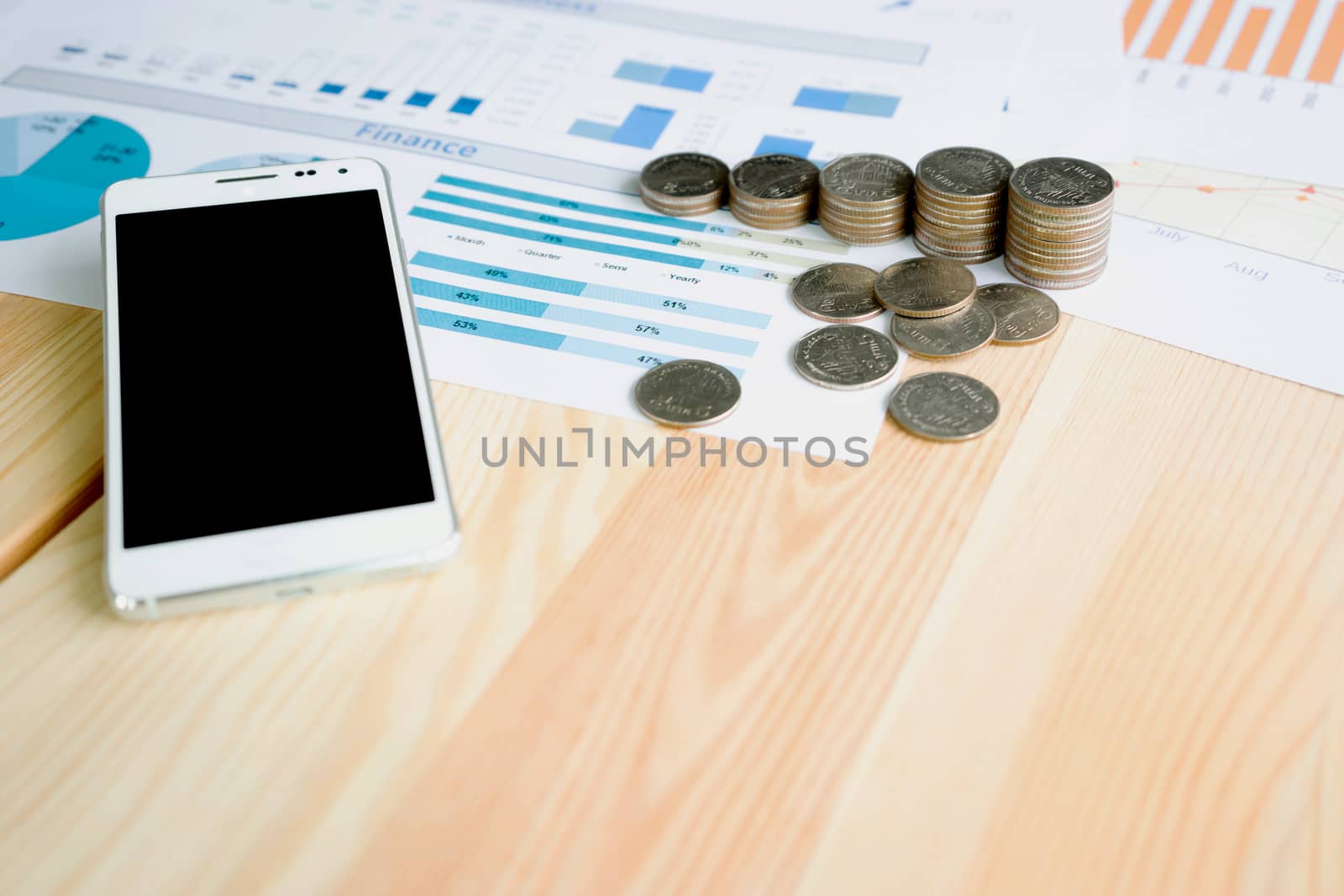Stack coin and smartphone on table with statistic graph diagram