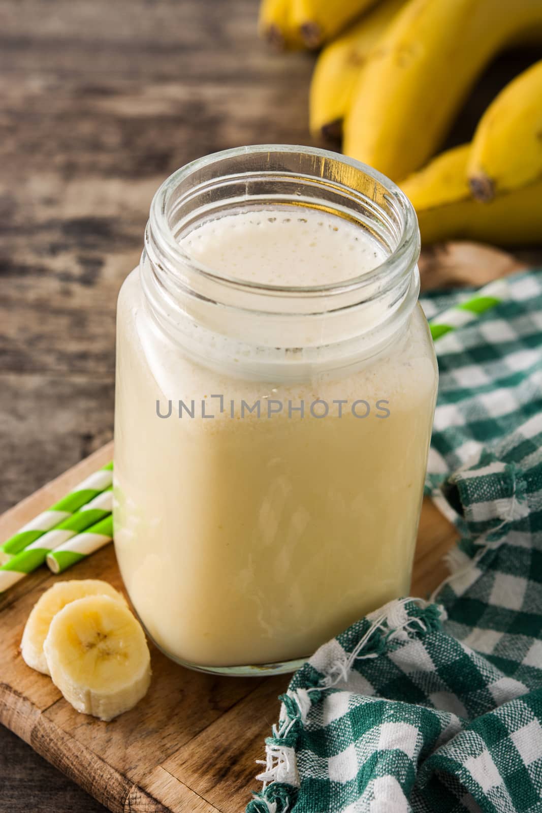 Banana smoothie in glass on wooden table.