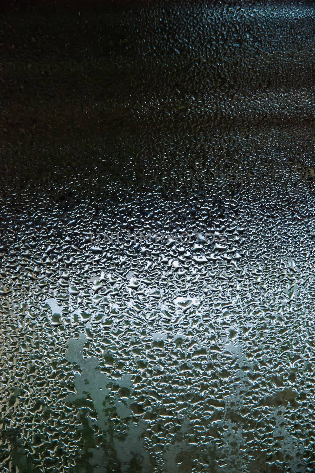 Water drops on a glass, with reflections on a dark background