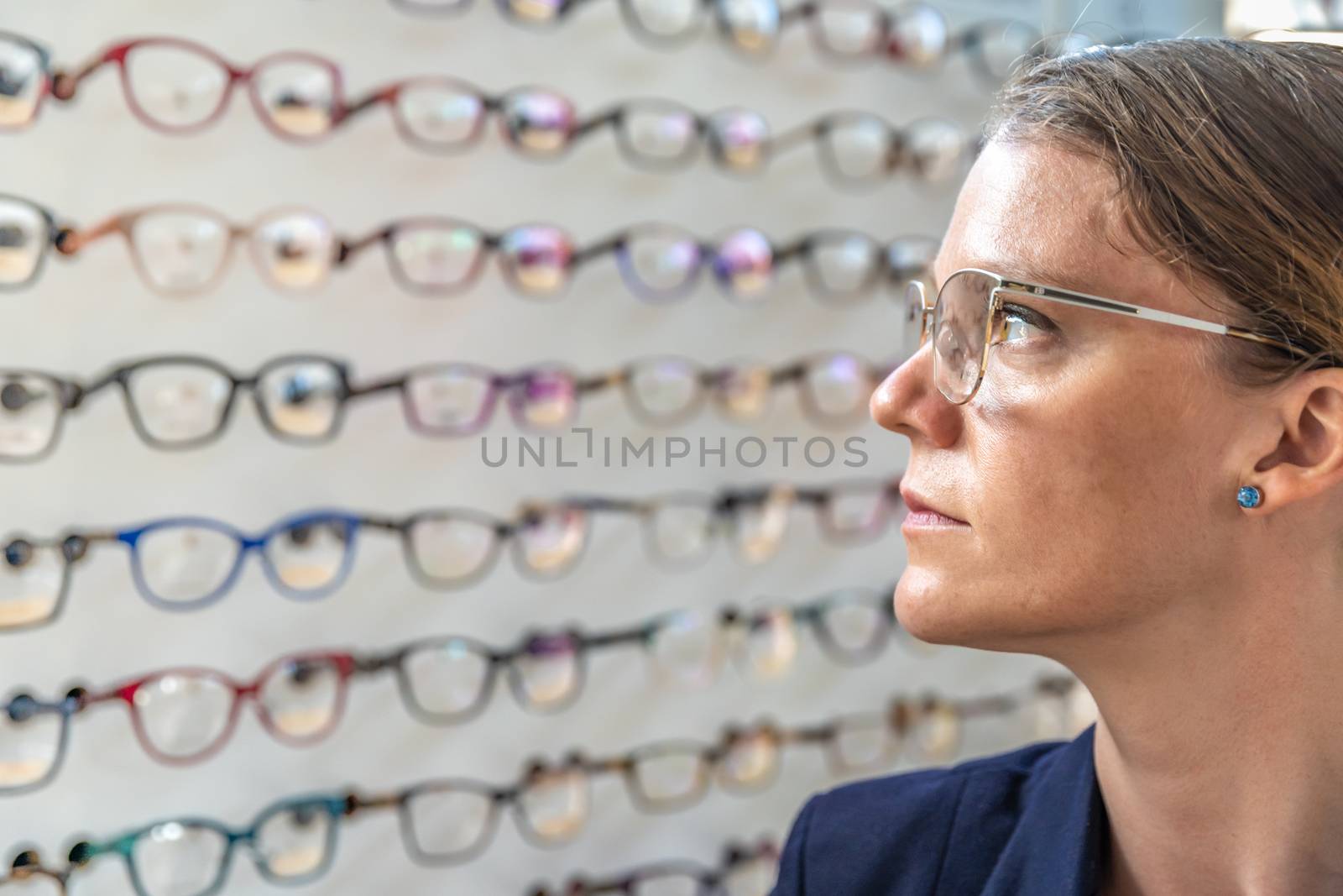 the glasses are selected and tested by a woman in an optics store. copy space by Edophoto