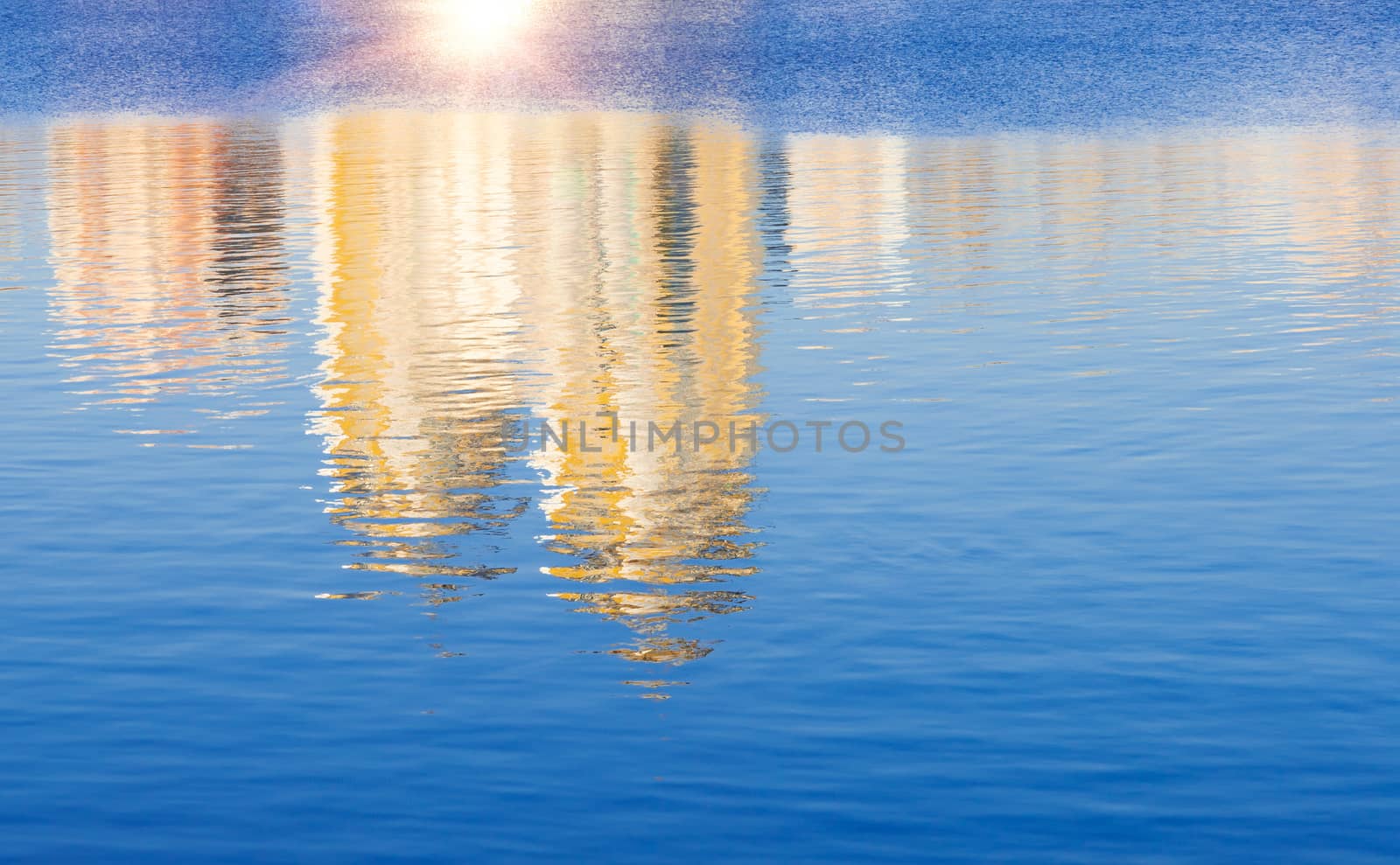 Sky, sun and buildings reflecting in the calm water of the Dnieper river in Kiev, Ukraine