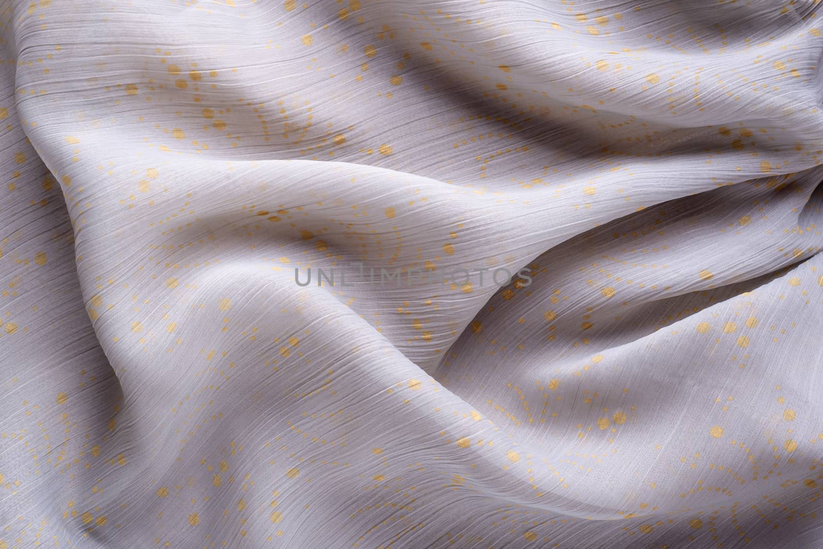Soft folds of a light pink synthetic fabric texture with yellow gold ornaments to be used as background