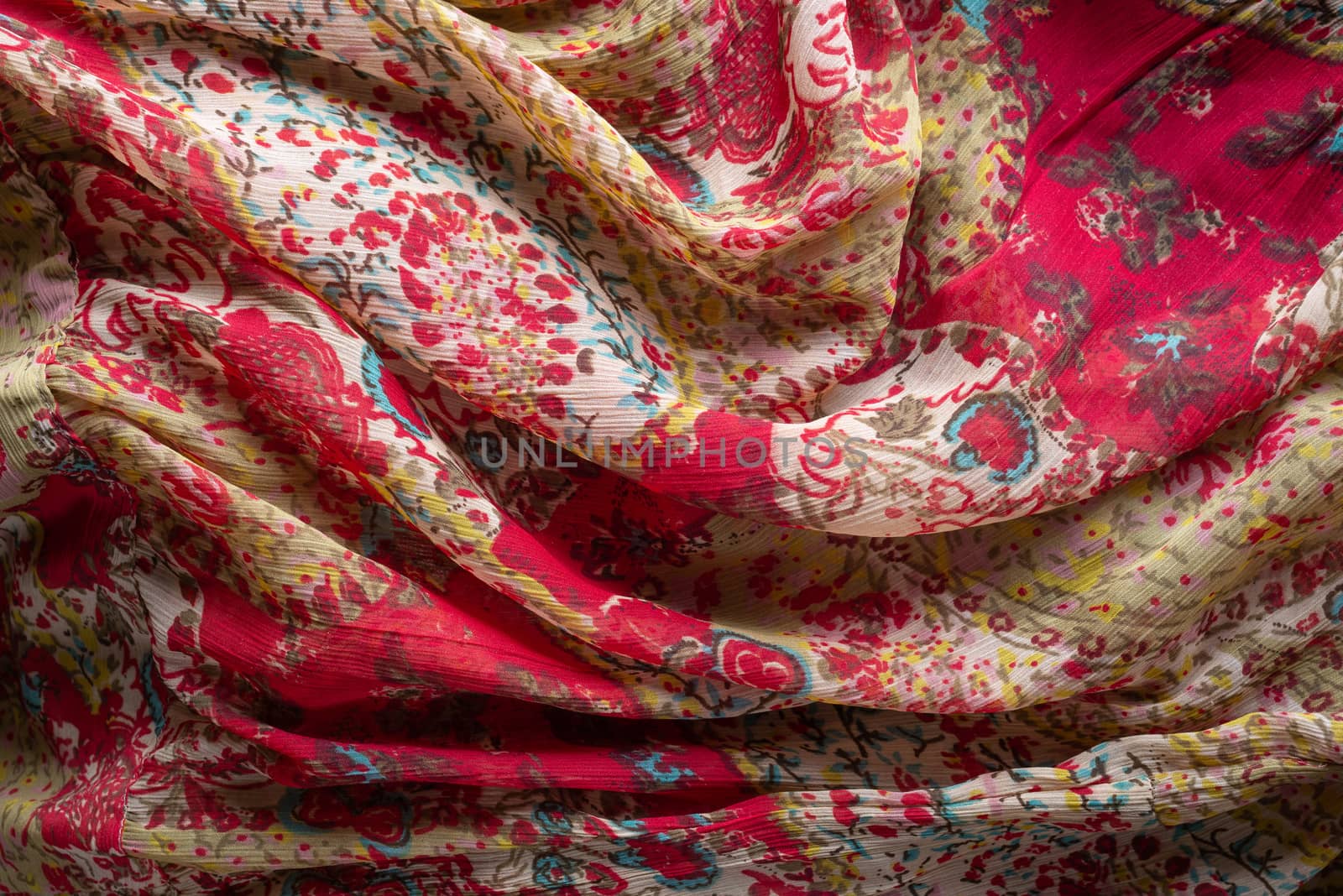 Soft folds of a multicolored synthetic fabric texture with an antique floral ornaments to be used as background