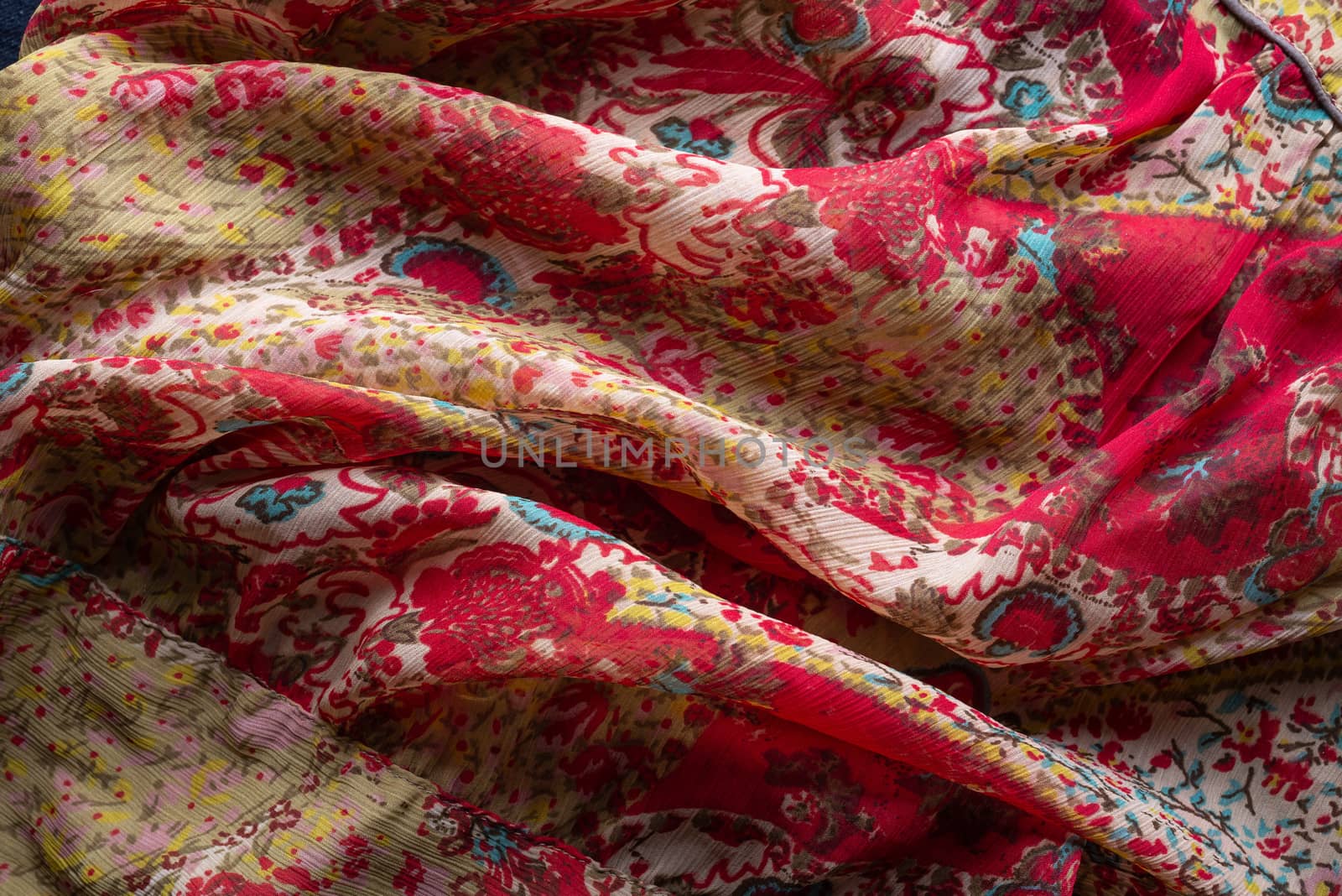 Soft folds of a multicolored synthetic fabric texture with an antique floral ornaments to be used as background