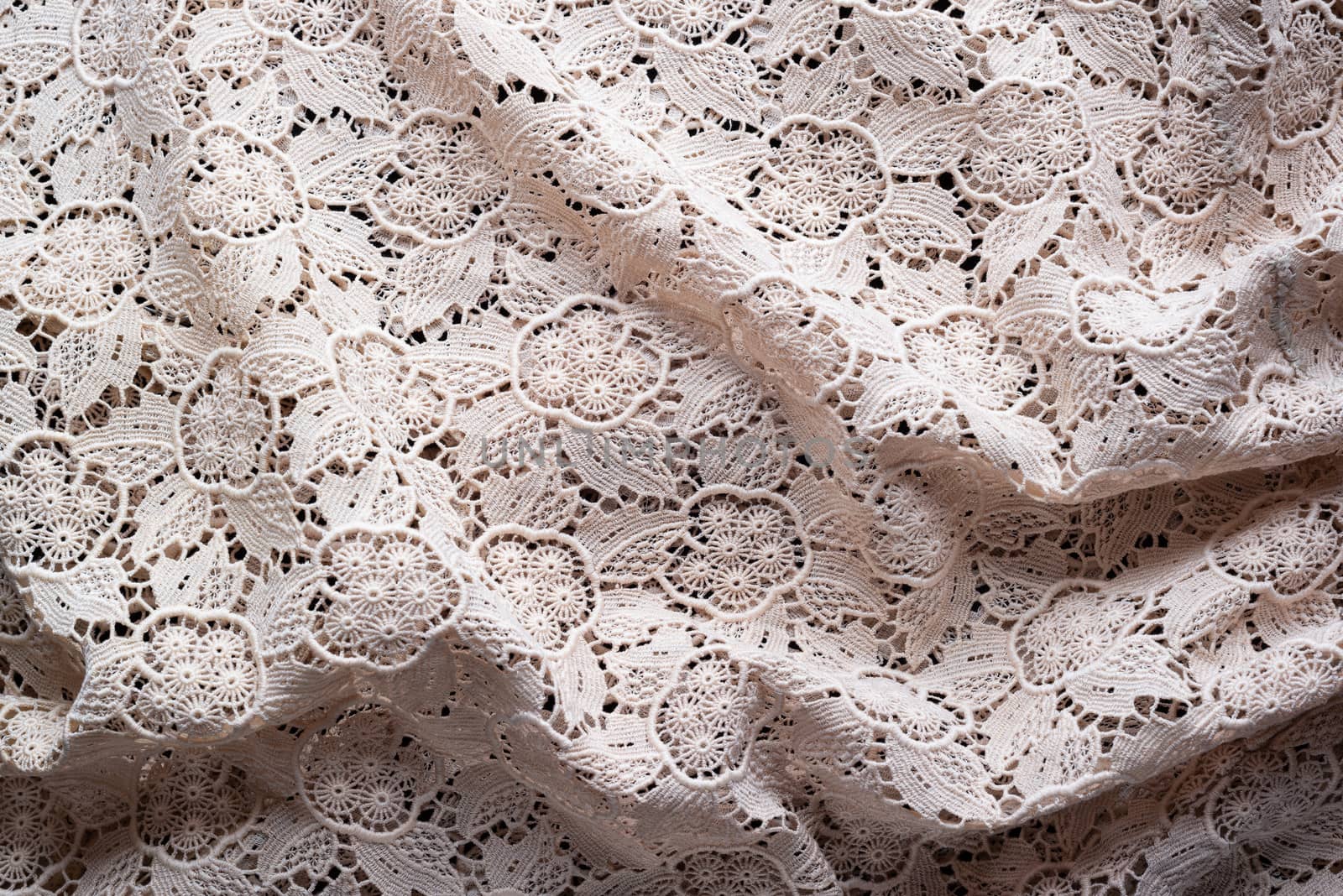 Soft folds of a white genuine traditional lace placemat to be used as background