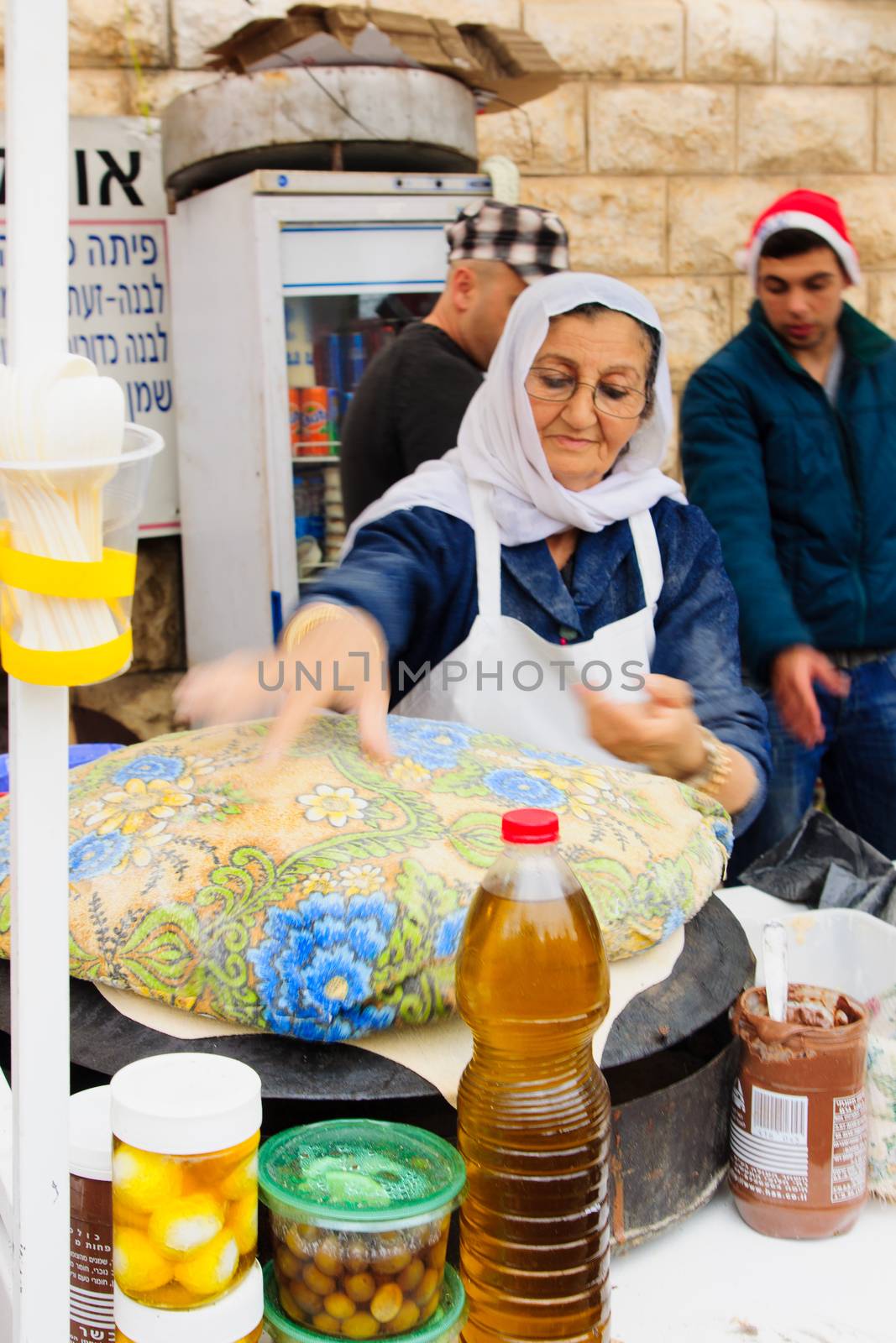 NAZARETH, ISRAEL - December 19, 2014: A woman preparing pita bread, in a Christmas market food stall, in Nazareth, Israel