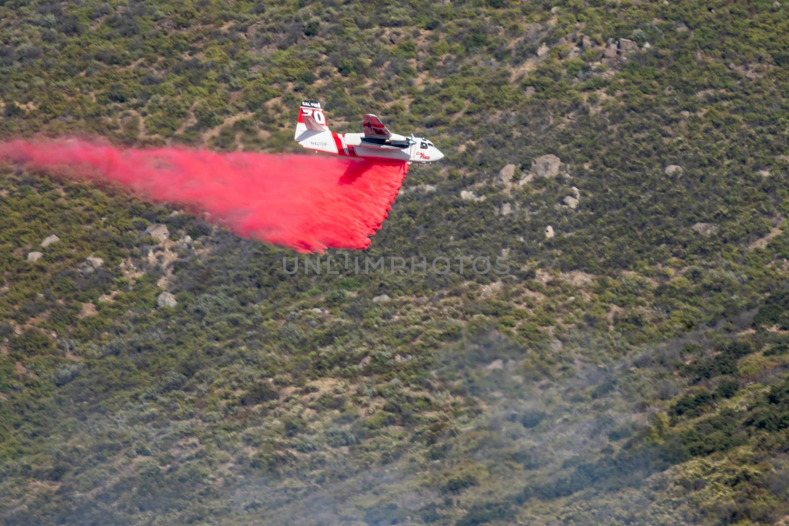 Winchester, CA USA - June 14, 2020: Cal Fire aircraft drops fire retardant on a dry hilltop wildfire near Winchester, California.