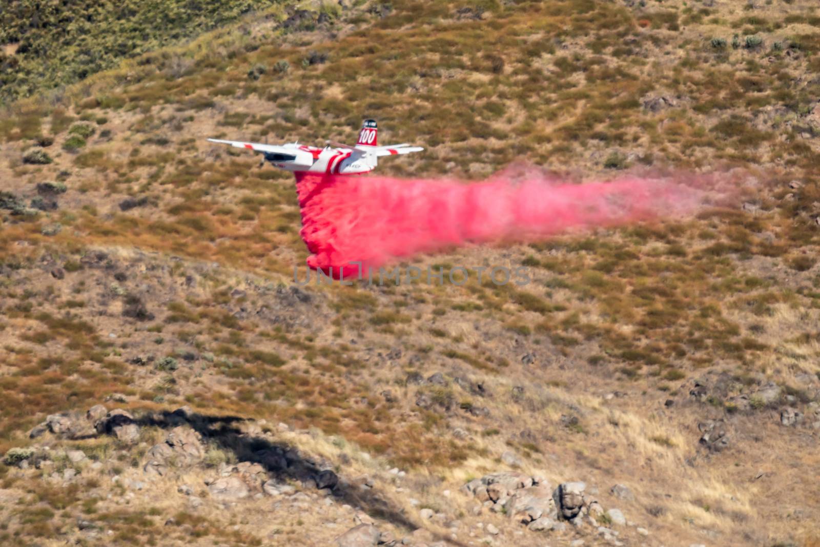 Winchester, CA USA - June 14, 2020: Cal Fire aircraft drops fire retardant on a dry hilltop wildfire near Winchester, California.